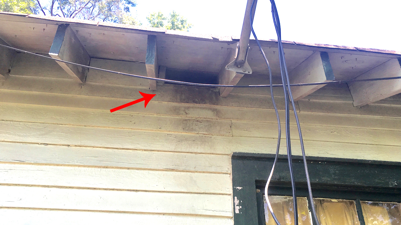 Large hole in house below eave where pests can enter attic