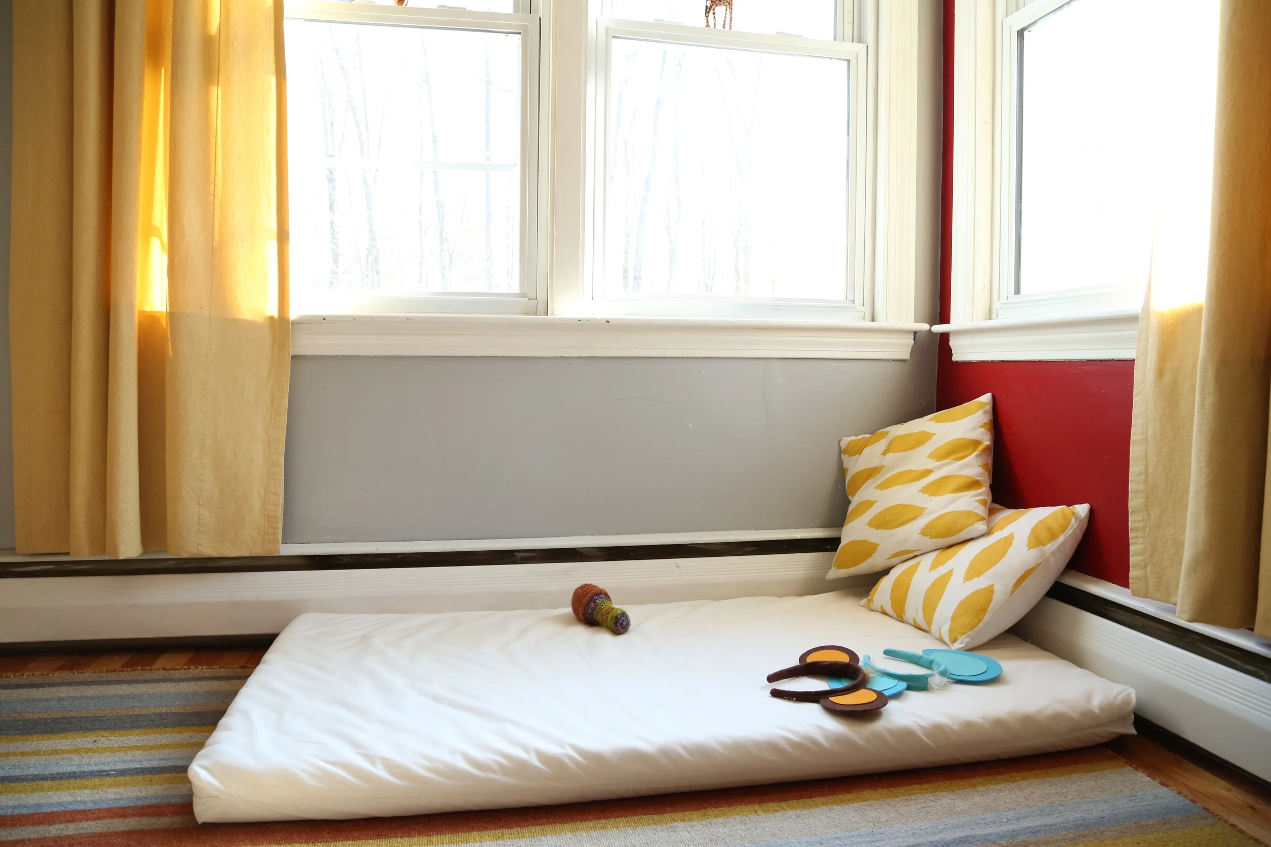 This is our resting bed and reading area. Every morning, they come here and look at books for about an hour while we sleep in. It's nice having an extra bed in case we have another child over. If we had a baby who couldn't crawl yet, I'd mount a mirror horizontally above it. But, we already had a walking baby by the time we moved here.