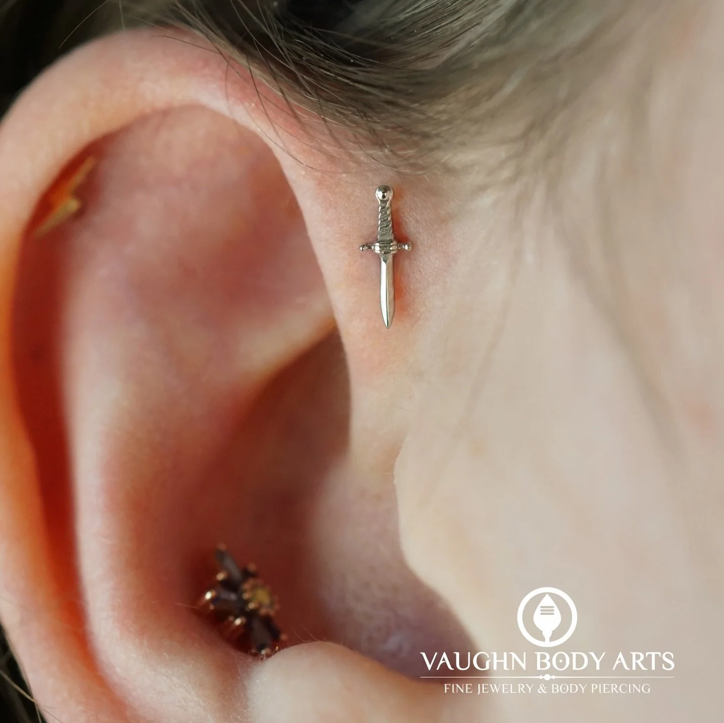 This lovely ear belongs to our wonderful client Ginger. 

For their new forward helix piercing they chose this white gold dagger. 

For their healed conch piercing, they picked out a lovely &ldquo;Half MiniNova&rdquo; made of Rose Gold with Tanzanite