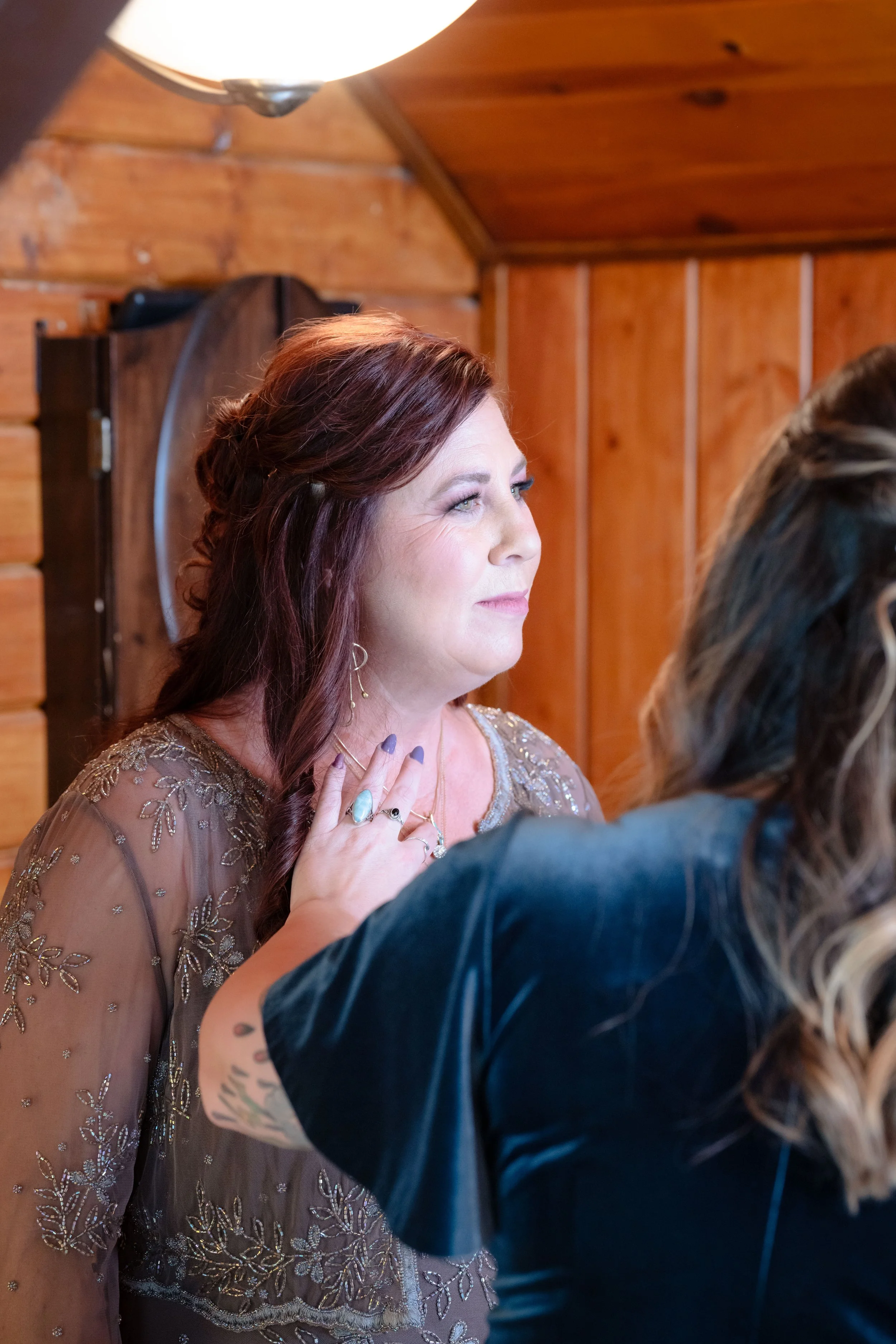 the mother of the bride looks towards her daughter. she is wearing soft glam makeup 