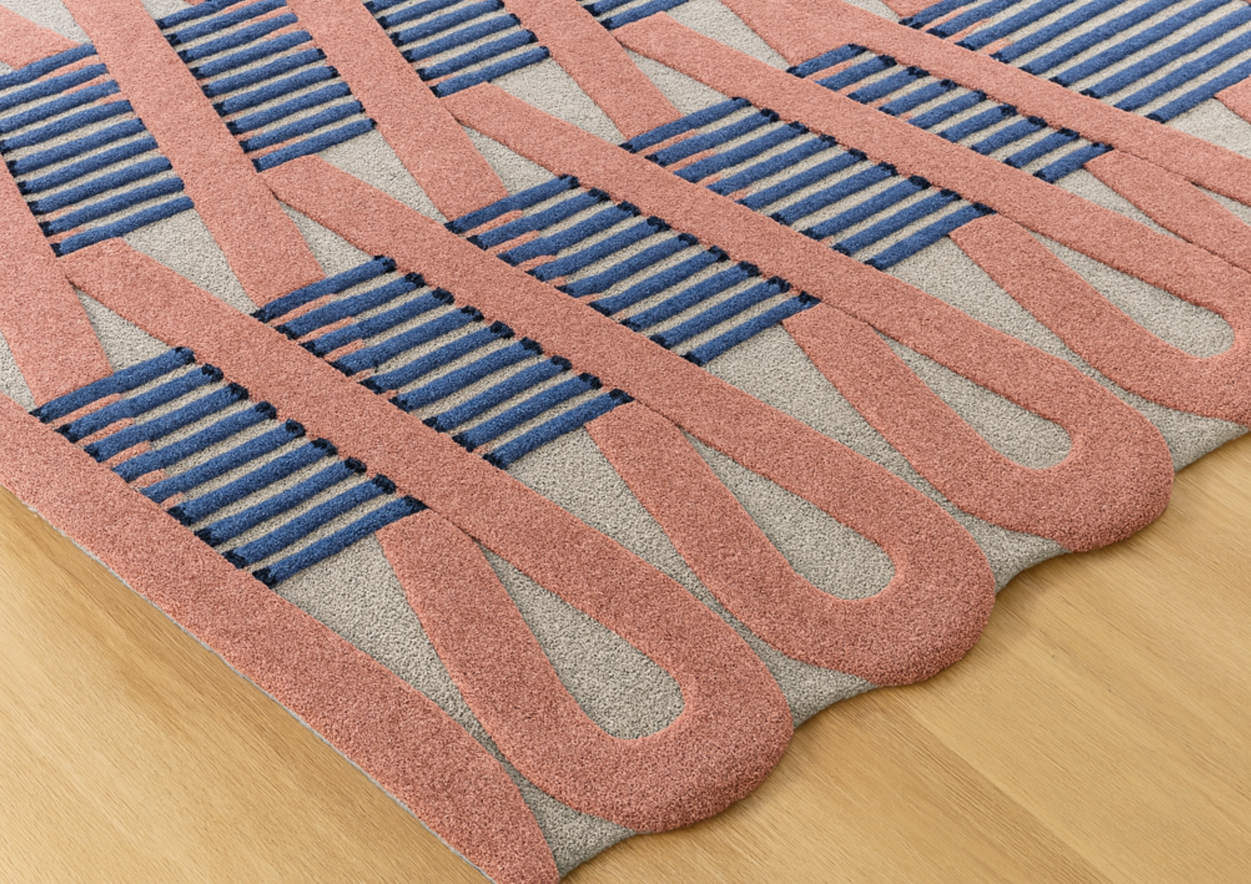 Abstract geometric rug in coral pink, blue, and gray, showcasing bold modern design for contemporary interiors.