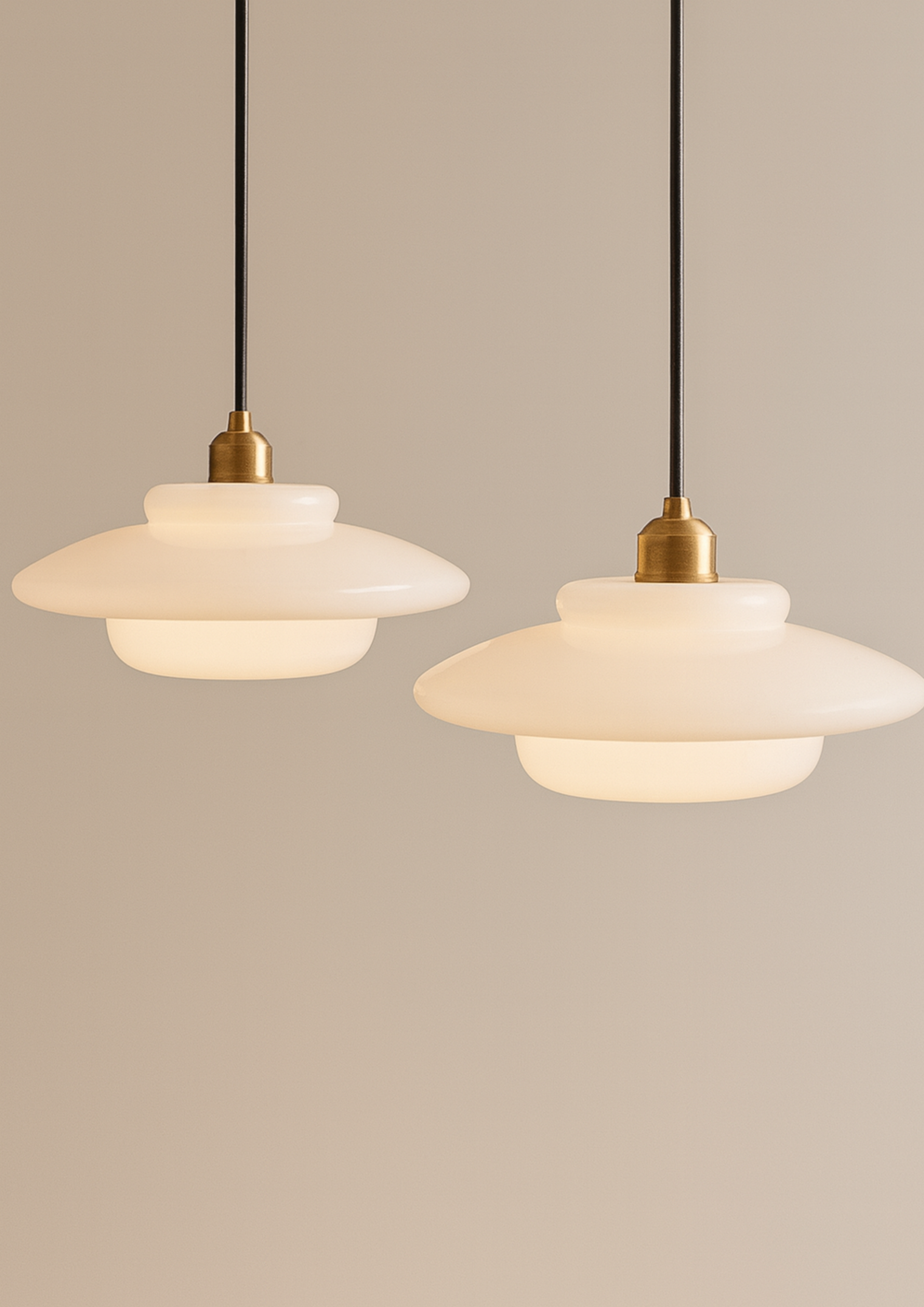 Pendant lights with layered frosted glass shades and brass details, suspended against a neutral backdrop, highlighting Scandinavian modern lighting design.