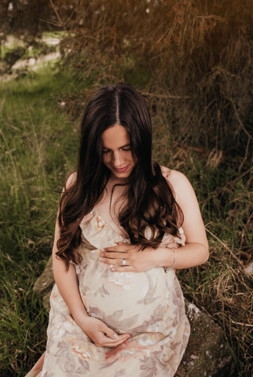 A pregnant lady looking down at her baby bump