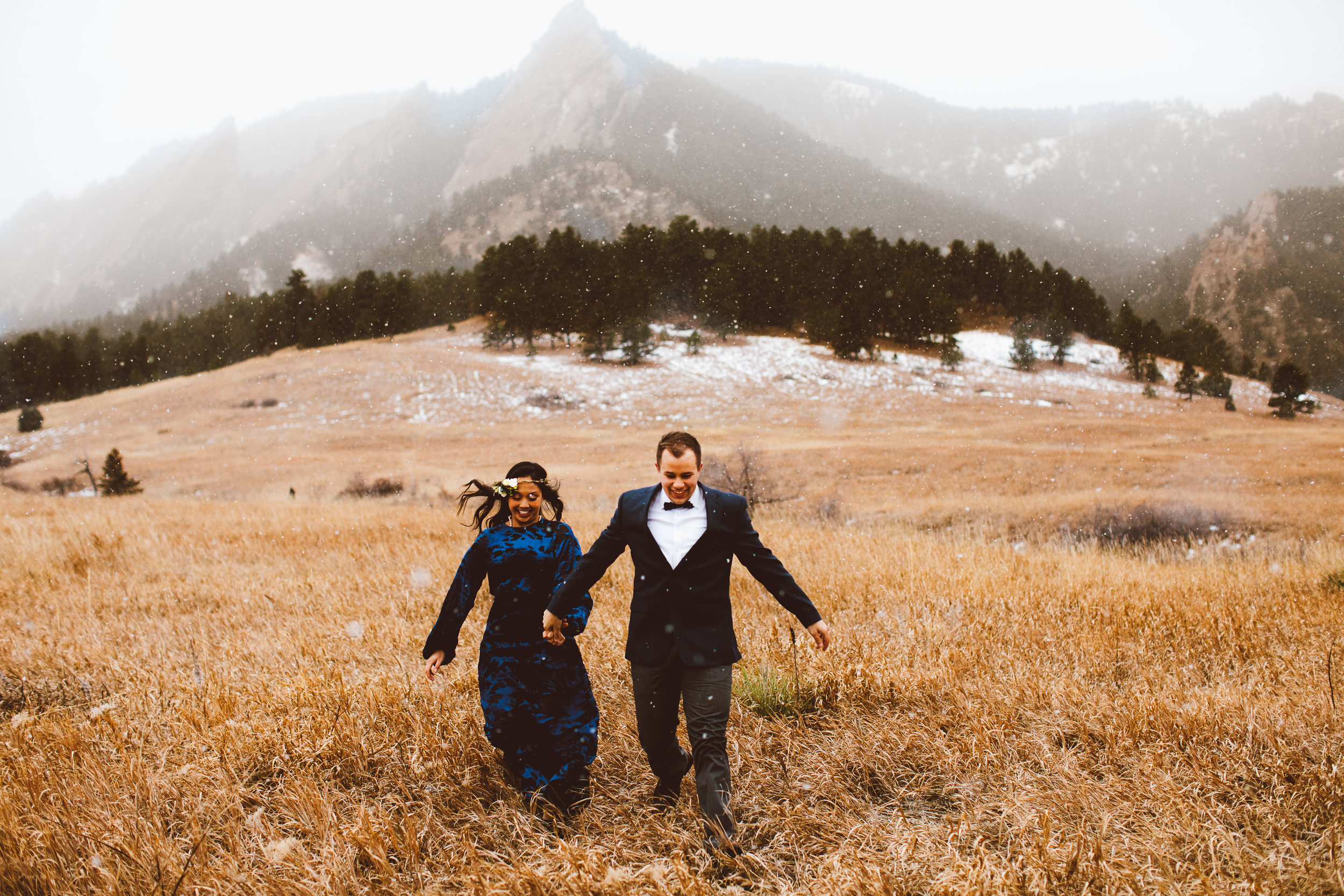 Eloped couple running through field in snow in Boulder Colorado