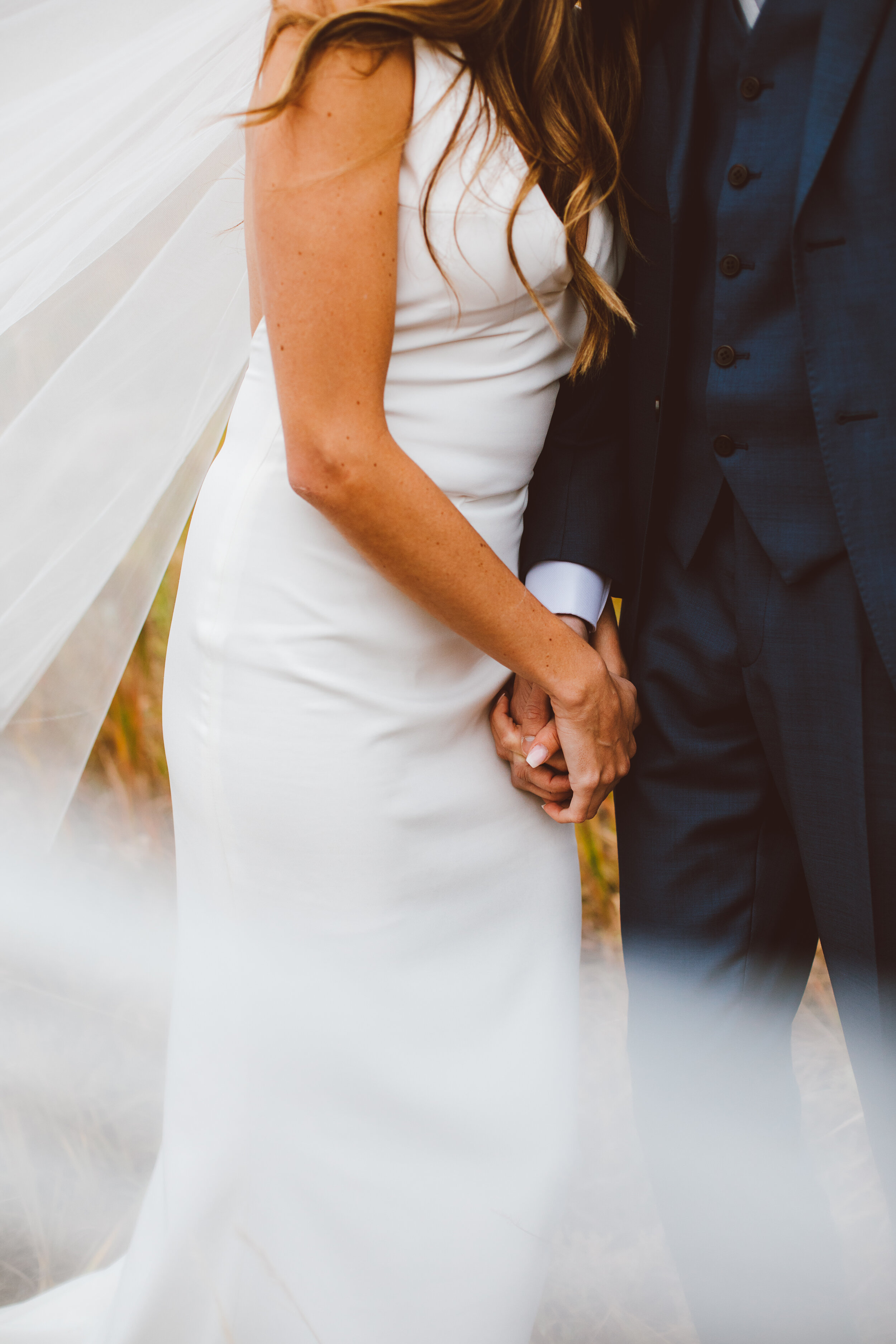 Bride and groom holding hands with wedding veil in Boulder, Colorado