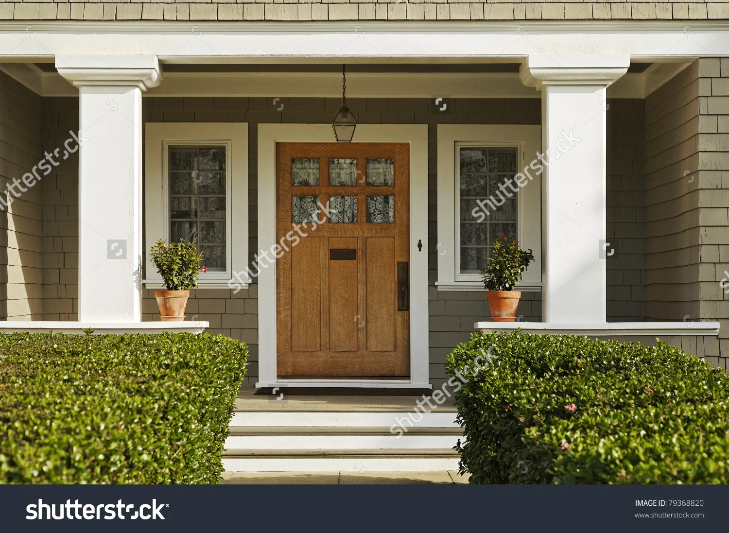 stock-photo-a-concrete-walkway-bordered-with-hedged-shrubs-leads-to-the-front-door-of-a-home-there-are-windows-79368820.jpg