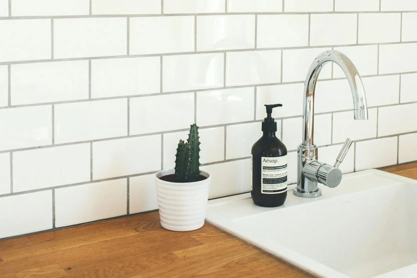 A sink with a wood counter and a white tile backsplash