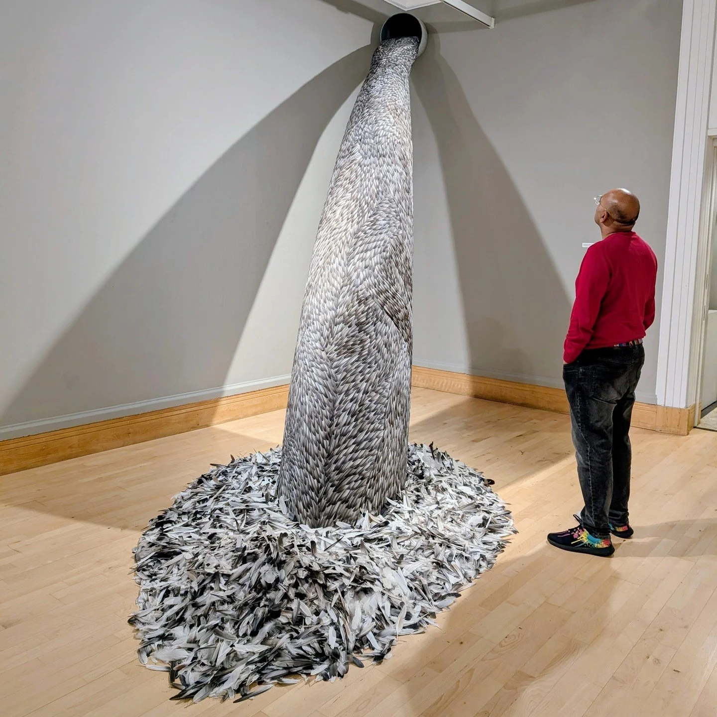 Feathers surround me. Some spew out of a corner of the gallery in a cascade, others are encased within a vitrine as if they belong to a creature that&rsquo;s concealed within the tightly wound structure made from deep green rooster feathers. 

Welcom