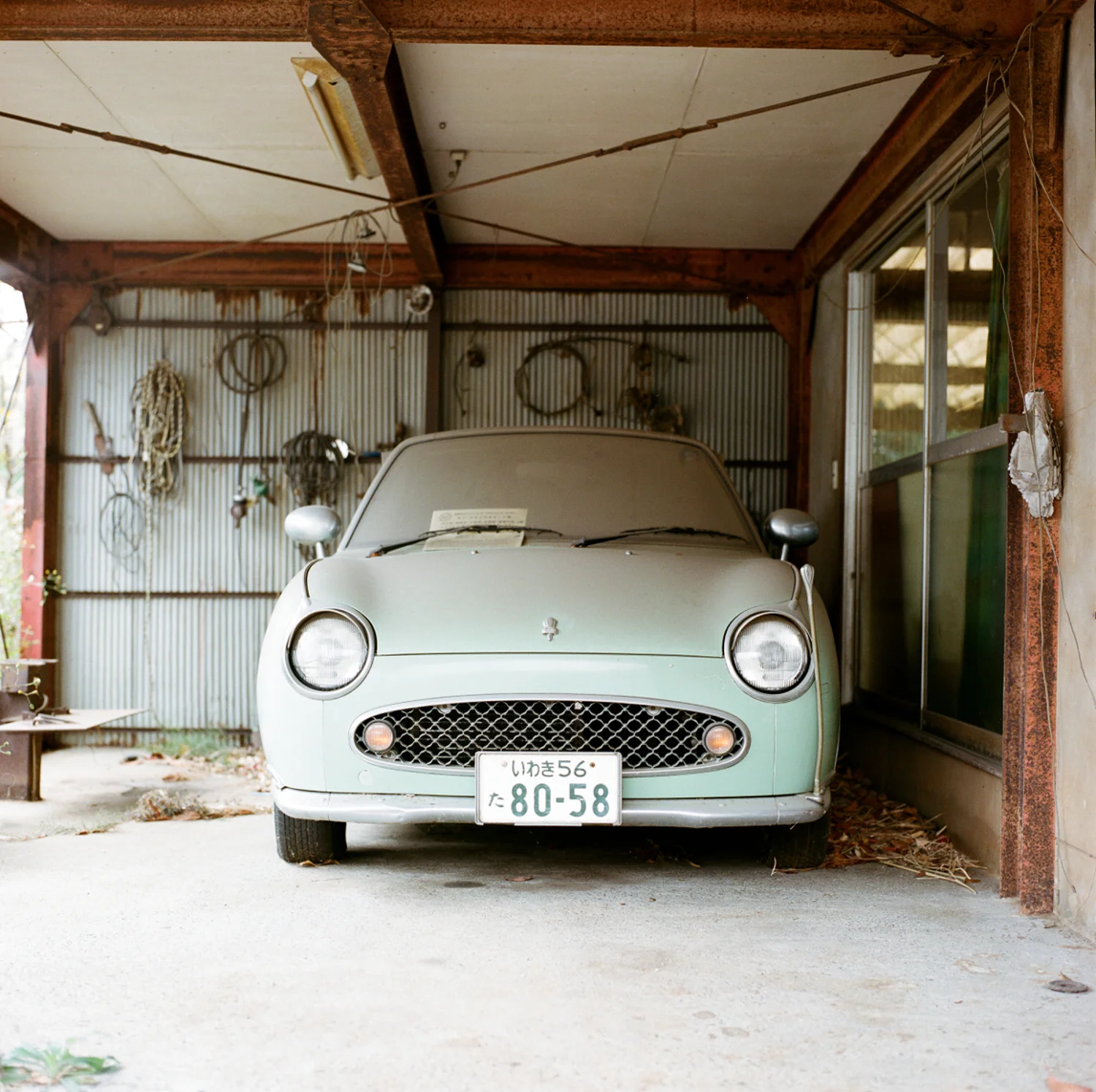 Une Nissan Figaro, voiture de collection construite à 20 000 exemplaires à la fin des années 1980. Elle prend la poussière depuis plus de quatre ans et attend le retour de son propriétaire.