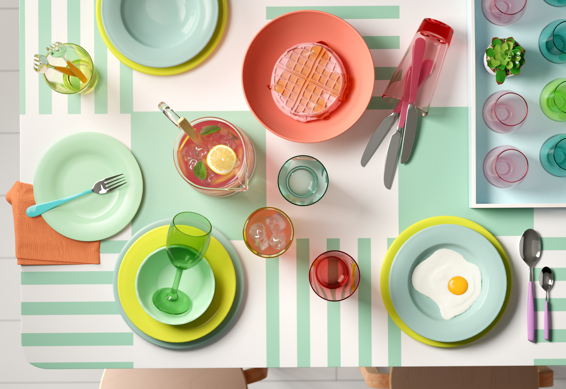 Colorful table setting with plates, glasses, a fried egg, a waffle, a loaf of bread, a pitcher of lemonade, and small potted plant on a green and white striped tablecloth.