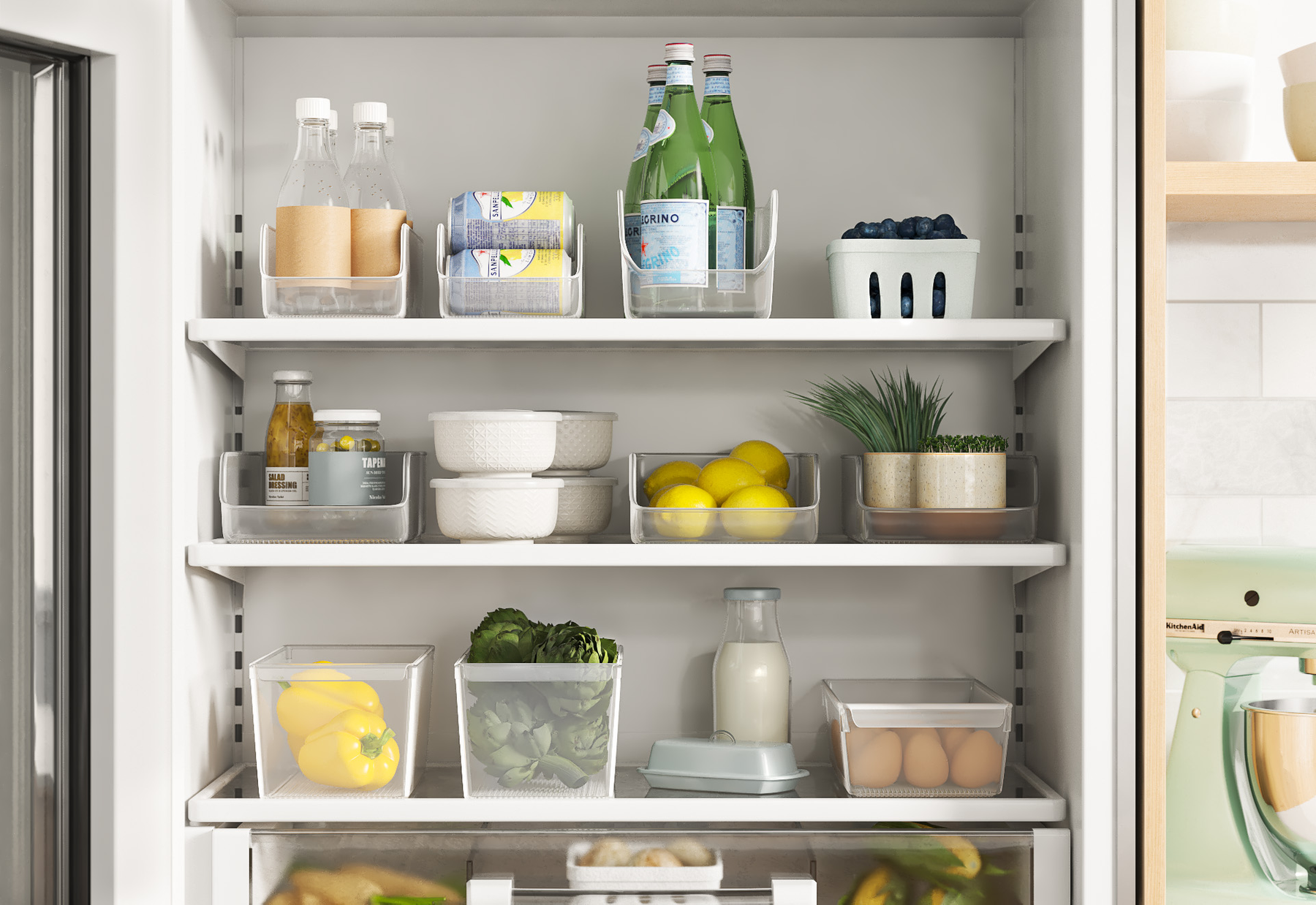 Open refrigerator door revealing shelves with bottled water, canned drinks, blueberries, salad dressing, lemons, lettuce, eggs, and other fresh produce.