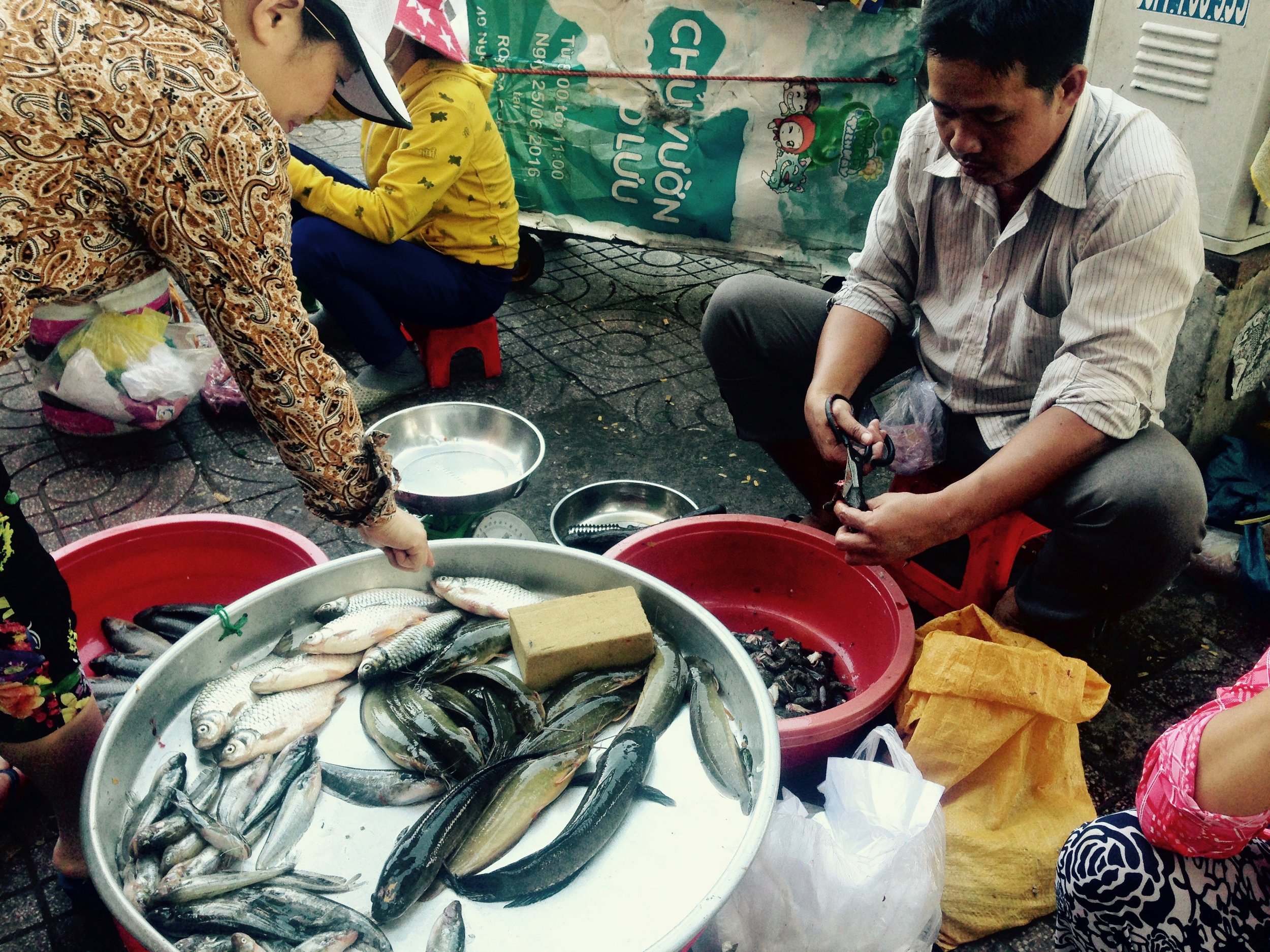 Market man is cutting out the insides of a poor frog