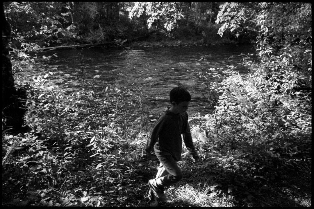 black and white photograph of a young boy at the mckenzie river in oregon
