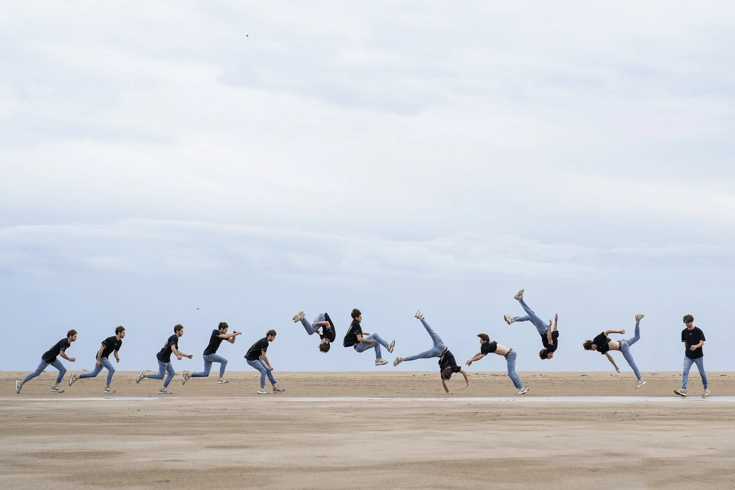 A sequence of a young man performing a backflip on a beach, captured in multiple stages from running to jumping to flipping.