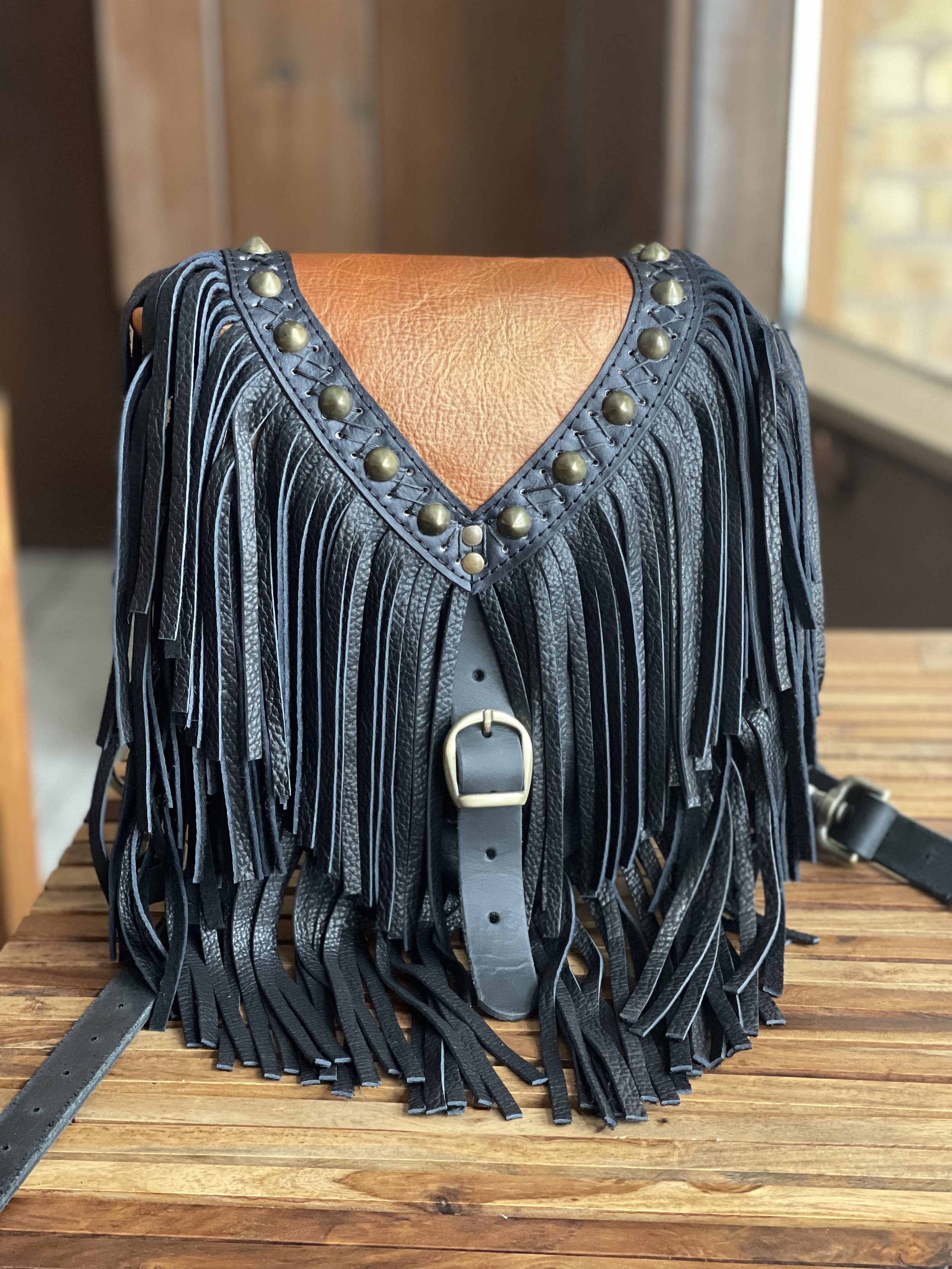 MINI BRITTANY CONVERTIBLE BACK IN HAND DYED DESERT GOLD TO COAL. CRISS CROSS HANDSTITCHING. STUDS. ANTIQUE BRASS HARDWARE. BLACK BISON LEATHER FRINGE.