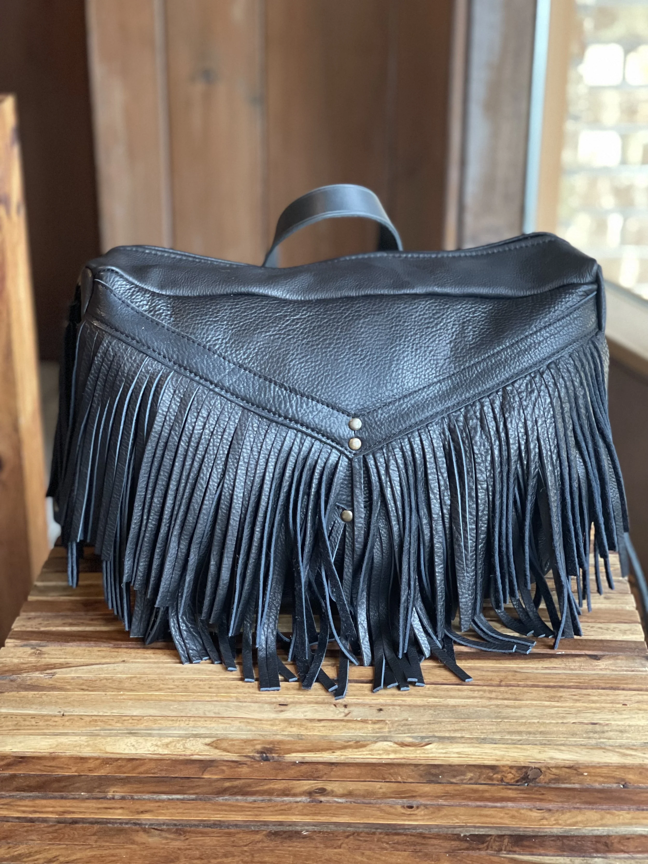MELISSA CONVERTIBLE BAG IN BLACK BISON LEATHER, ANTIQUE BRASS HARDWARE, AND ONE SIMPLE BLACK LEATHER HANDLE.