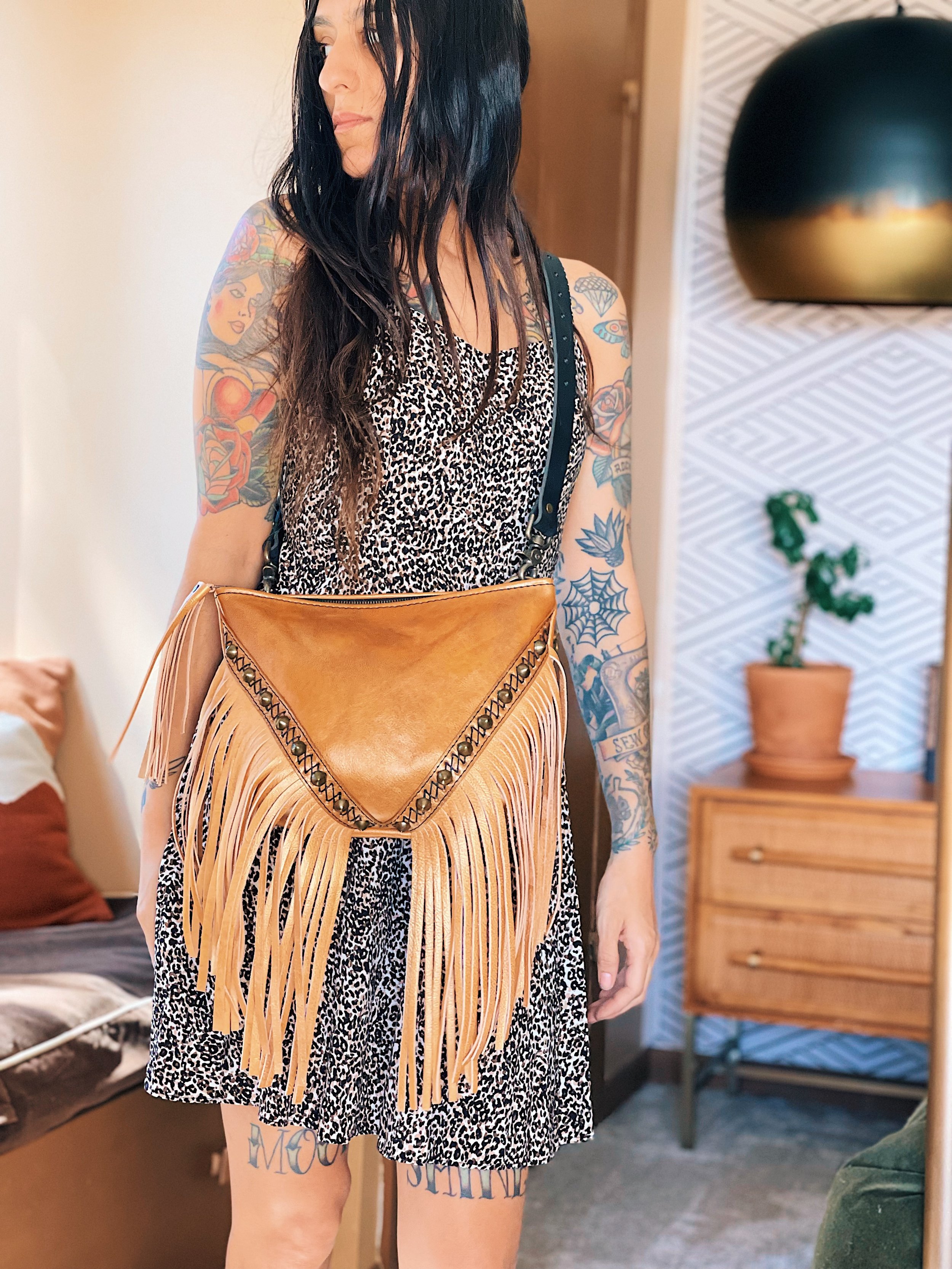  BODY: vegetable tanned cowhide leather, hand dyed desert gold.  FRINGE: vegetable tanned cowhide leather, hand dyed gold  ADDITIONS: criss cross hand-stitching and studs 