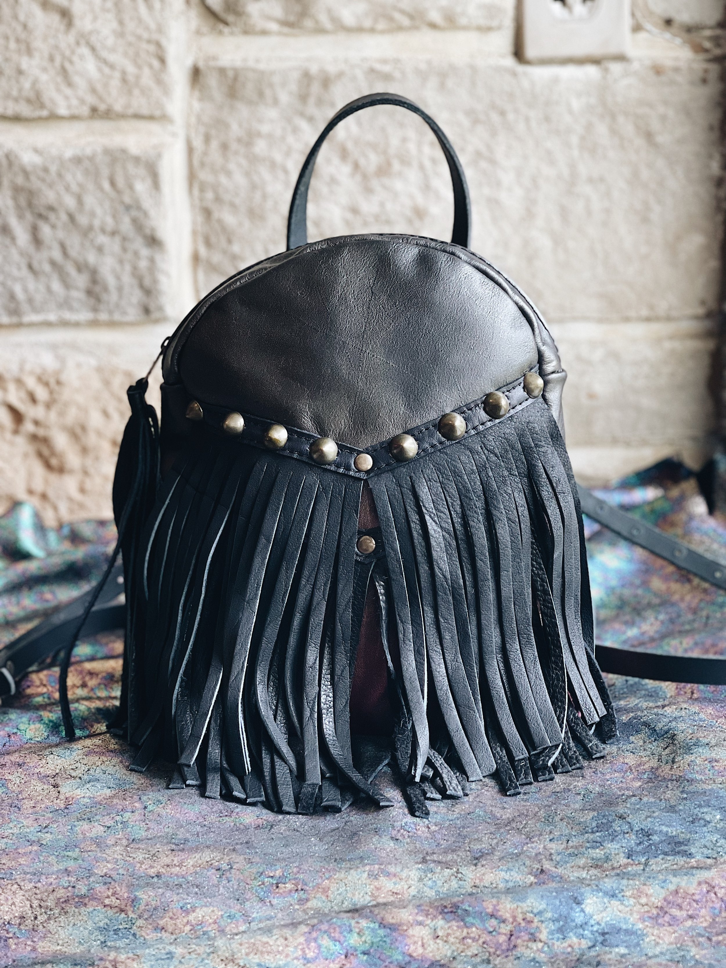 BODY: vegetable tanned leather, hand dyed pyrite and glam plum  FRINGE: black bison leather  ADDITIONS: studs and 1 simple handle 