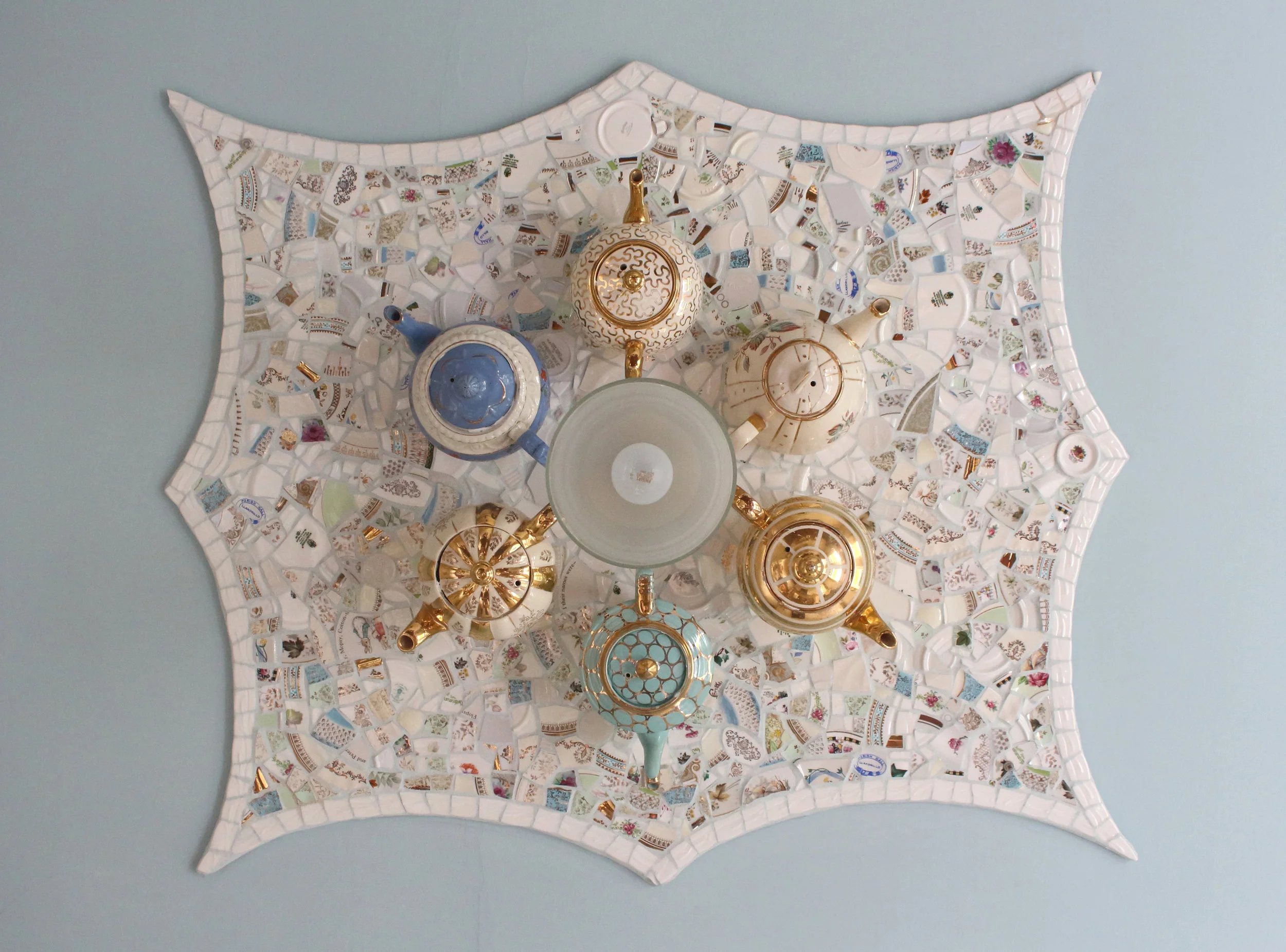 Antique teapot ceiling mosaic. This mosaic was built using recycled antique china and porcelain teapots fixed upside down onto the ceiling with a recycled china plate background ceiling rose and central light fixing. I was reminded of my love of the story of Alice in Wonderland as a little girl. Approx. 45ins. x 36 ins.