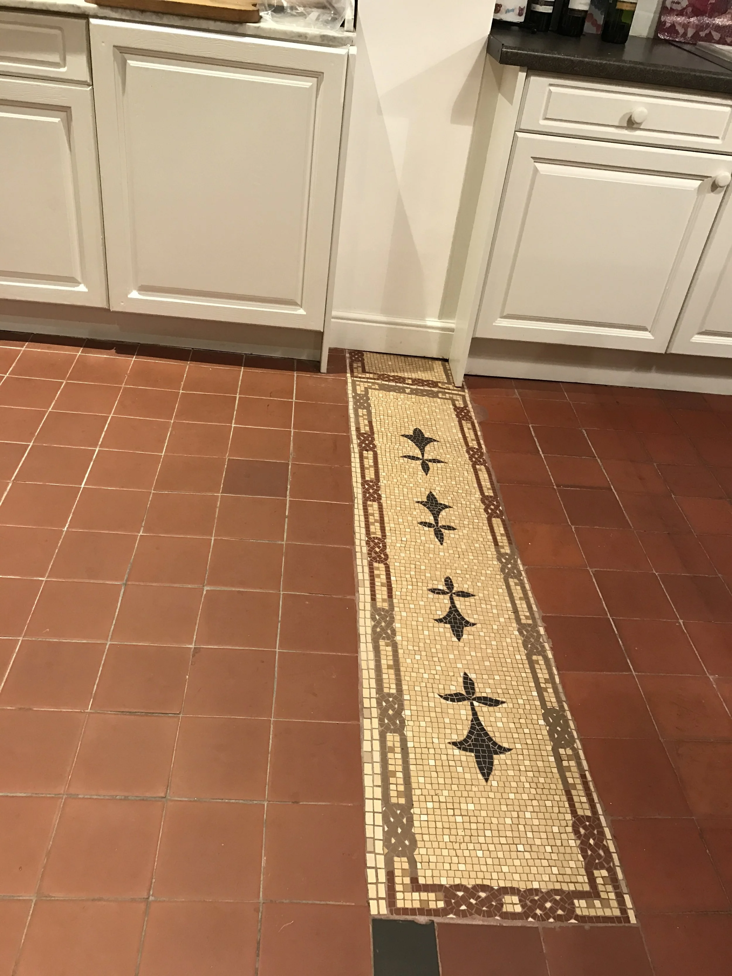 Kitchen floor mosaic inset with Celtic knot and Fleur de Lys. Where a partition wall was removed a mosaic inset is the perfect solution to seamlessly join the two floor areas. Matt porcelain Mazurka and Winklemans tiles.