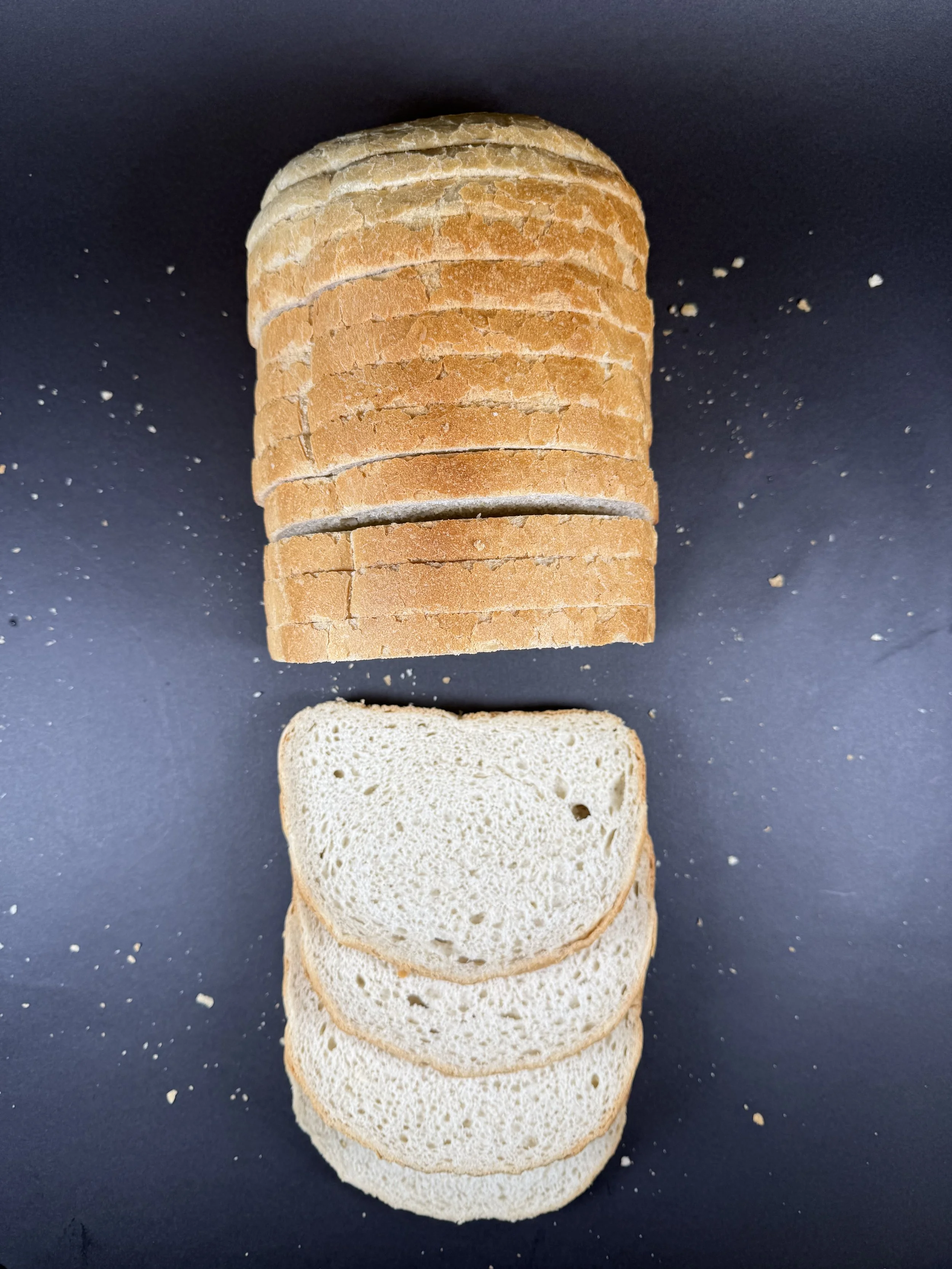 A white bloomer loaf sliced. Photograph taken from the top down, giving a birds eye view of the loaf