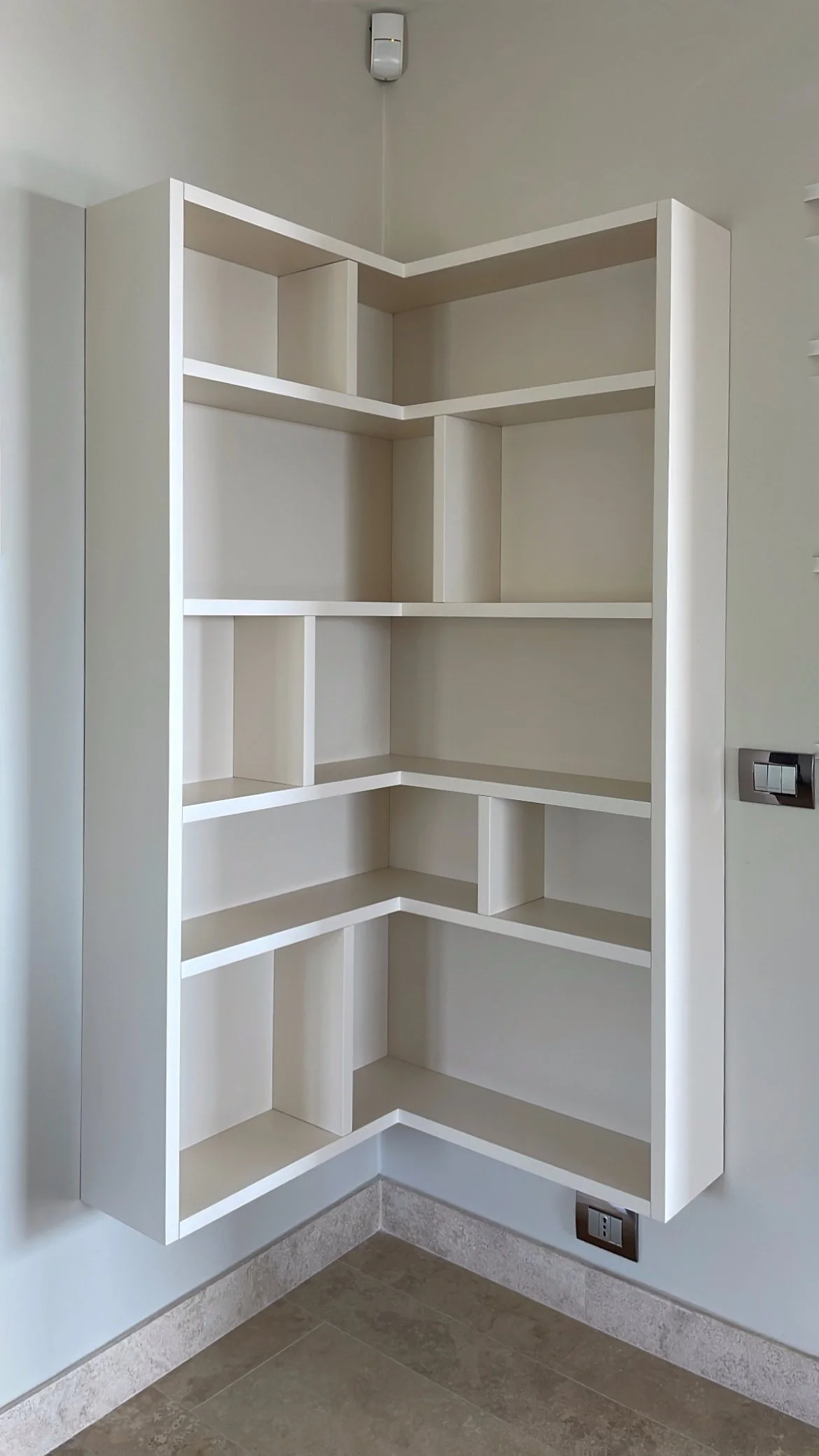  Libreria angolare sospesa, laccata opaca nella stessa tonalità della muratura su specifica del cliente. 