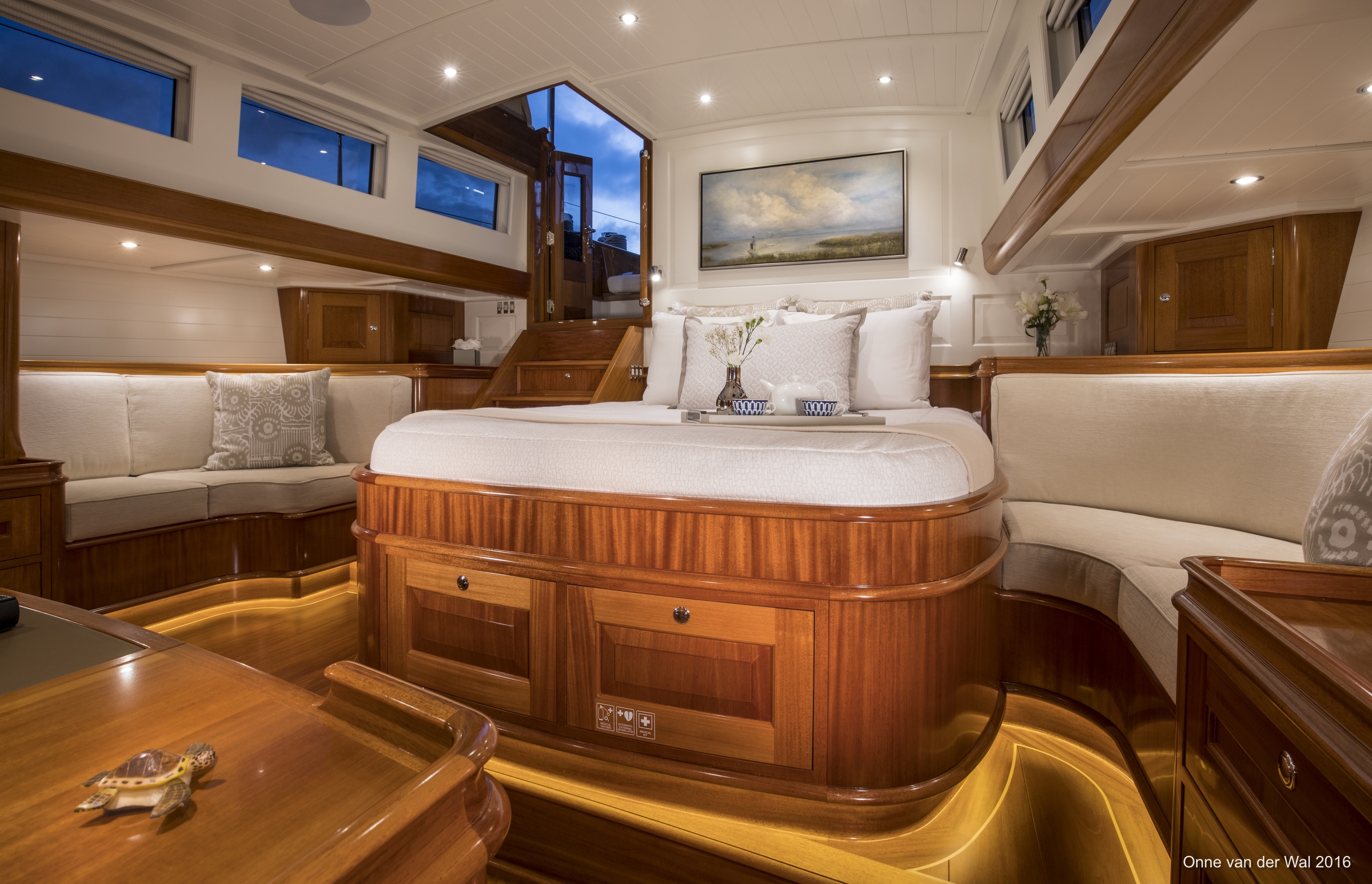 The master stateroom offers the yacht’s hands-on owner easy access to the aft cockpit, where he can play an active role in sailing. Here and throughout the boat’s interior, white-painted paneling is used strategically to keep the overall look from being too dark and heavy. Above the bed is a painting by Alabama artist Susan Downing-White that was commissioned by Waguespack to fit this space exactly and to evoke the owner’s memories of fishing by casting nets.