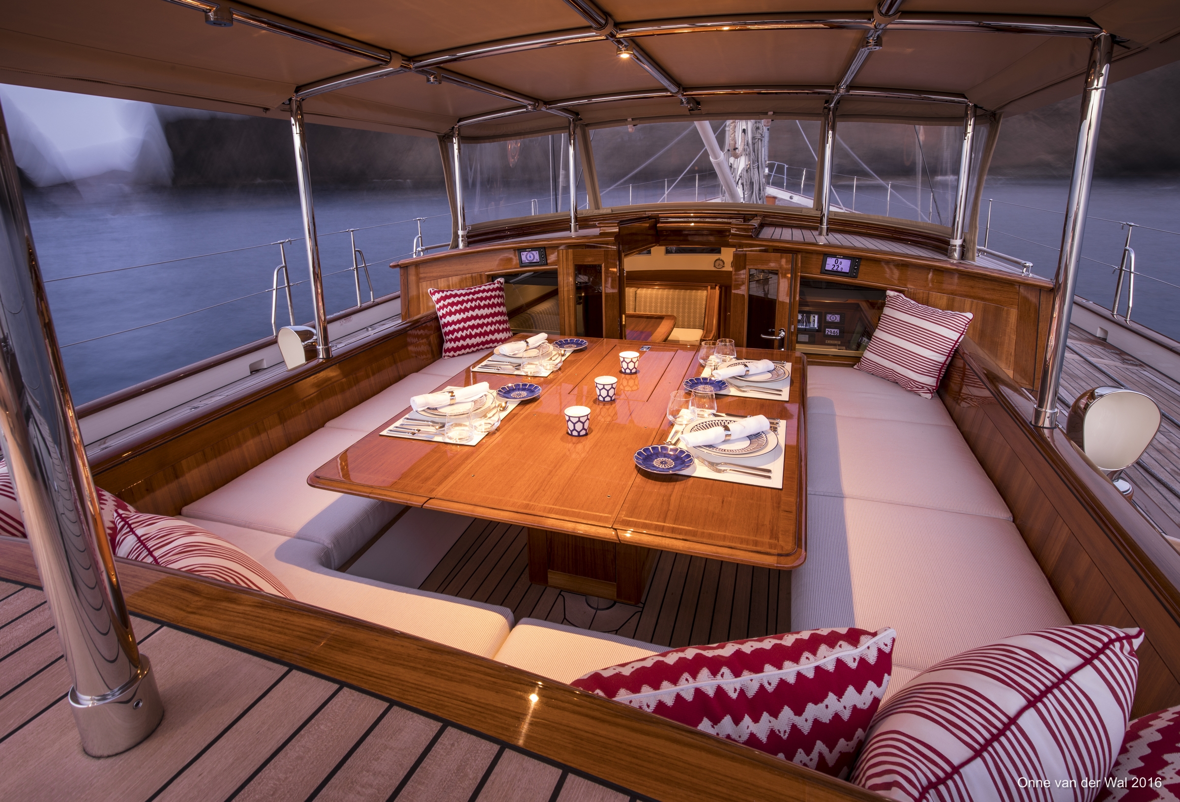The dining table in the forward cockpit is set with Hermes china and Christofle silverware and surrounded by banquette seating. Red patterned pillows link this area visually with the distinctive red hue of the underwater ship, the area below the waterline on the yacht’s aluminum hull.