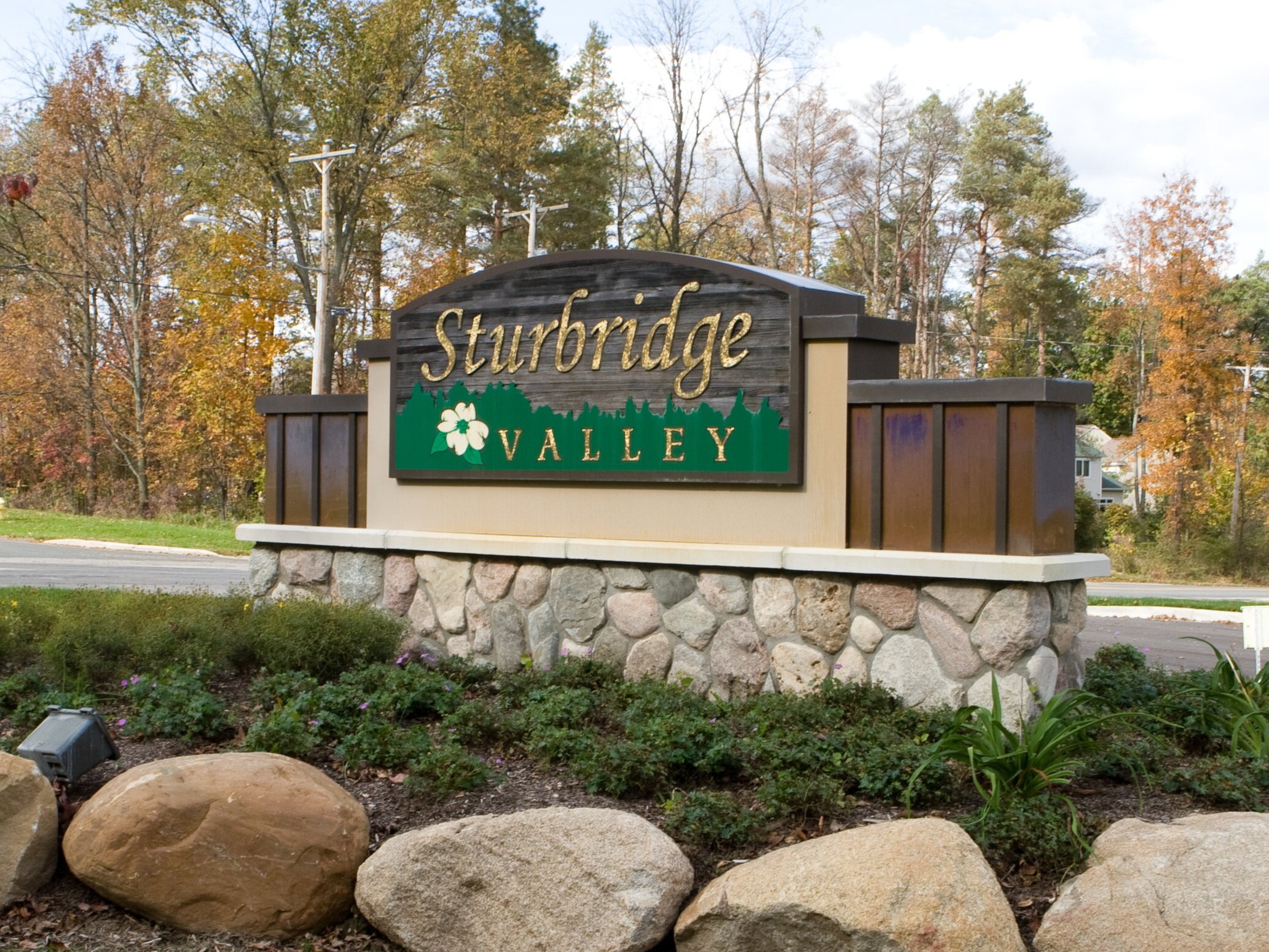  Monument sign with sandblasted cedar panel and gold leaf lettering with custom copper accent columns and a stone masonry base. 