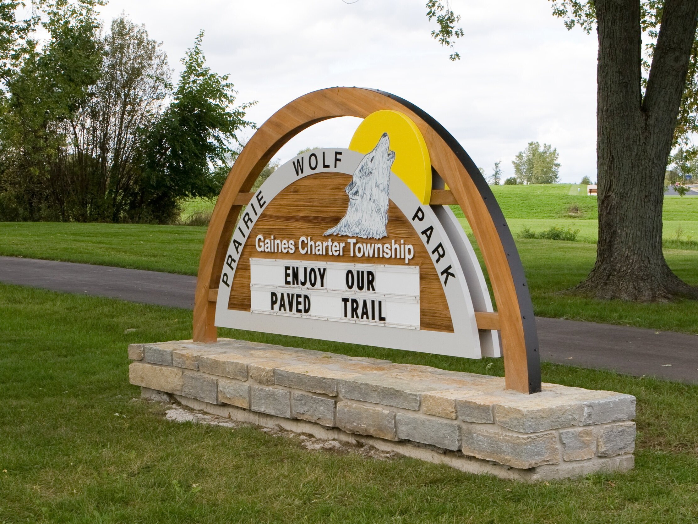  Monument sign with sandblasted Cedar panel with changeable copy area, arched cedar support and a stone masonry base. 