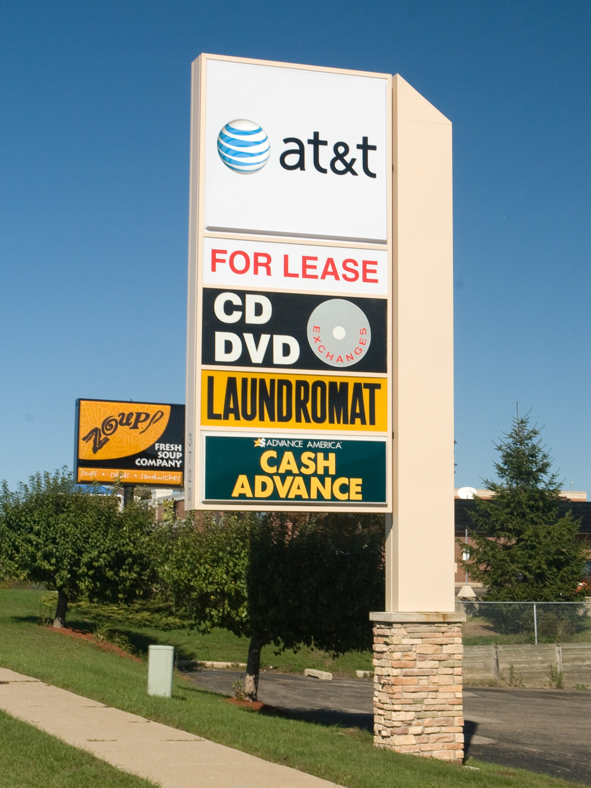  Flagmount multi-tenant pylon sign with polycarbonate faces and a stone column. 