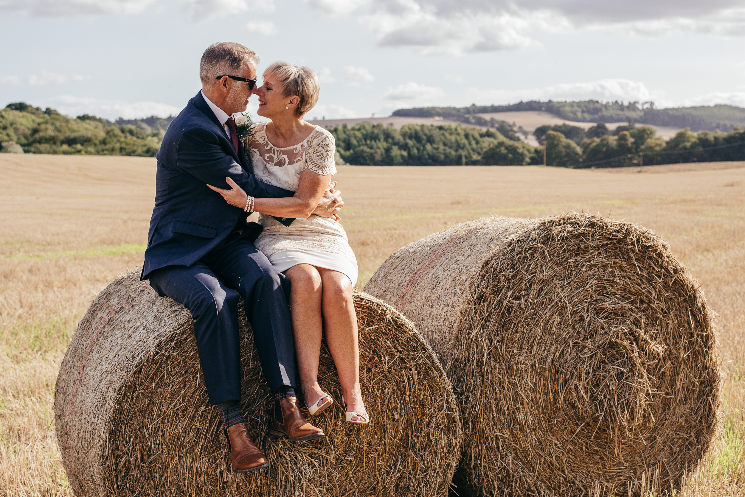Bride and groom sat on hay bales