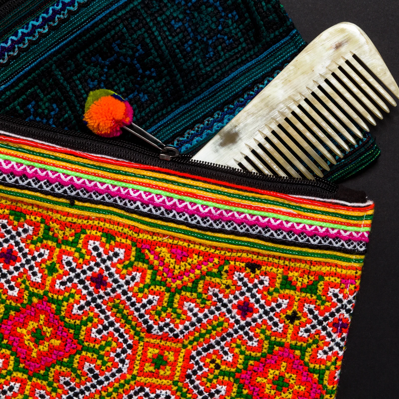 TEXTILES These pouches are made from the recycled skirts of the Hmong people. The fabric is richly and densely embroidered by hand, when the clothing is no longer needed or useful, the fabric is sold to be recycled into new items. Each bag will be unique in terms of the patterning, please choose by color palette-bright or subdued.