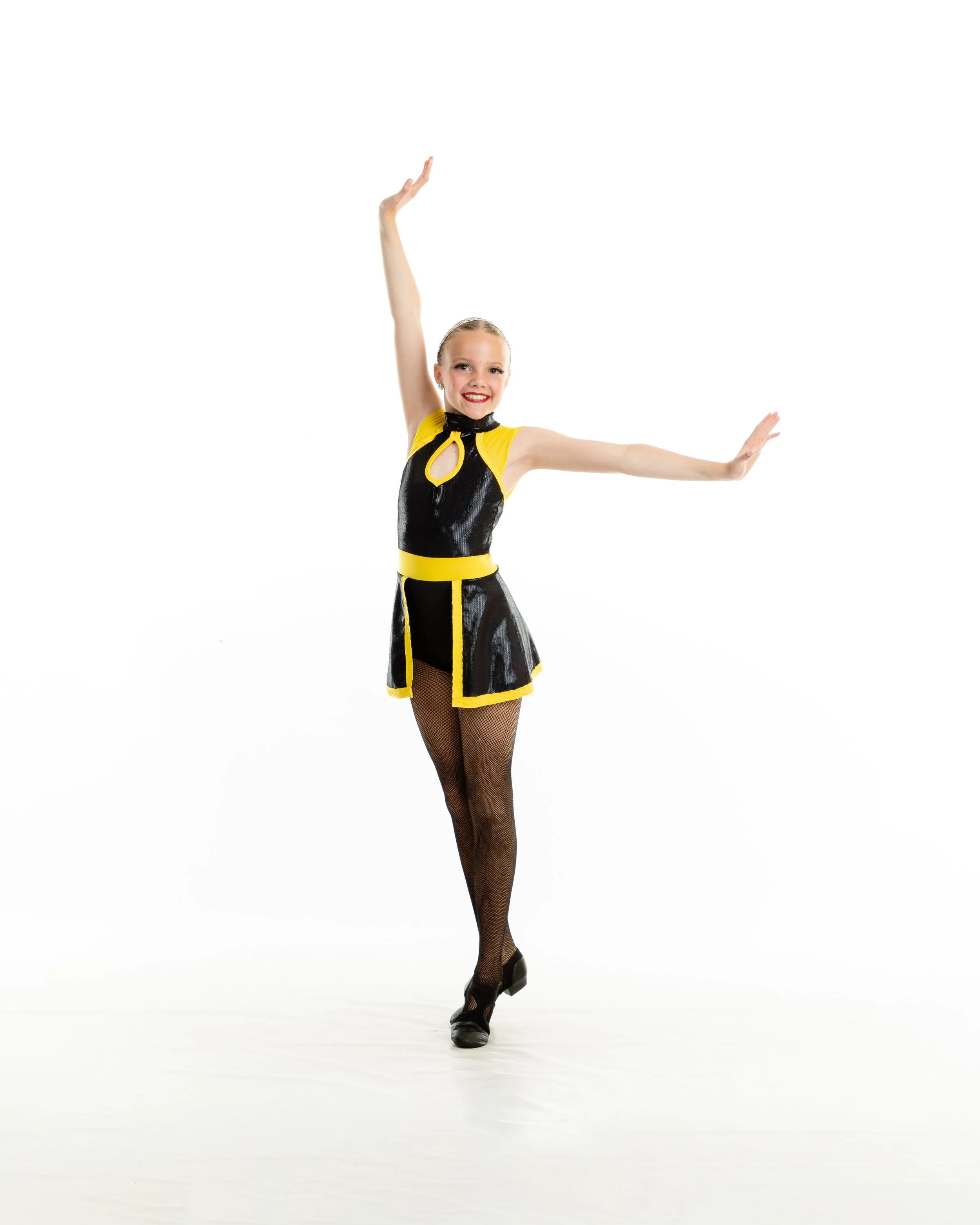Young girl performing a dance pose in a black and yellow costume with fishnet tights and dance shoes.