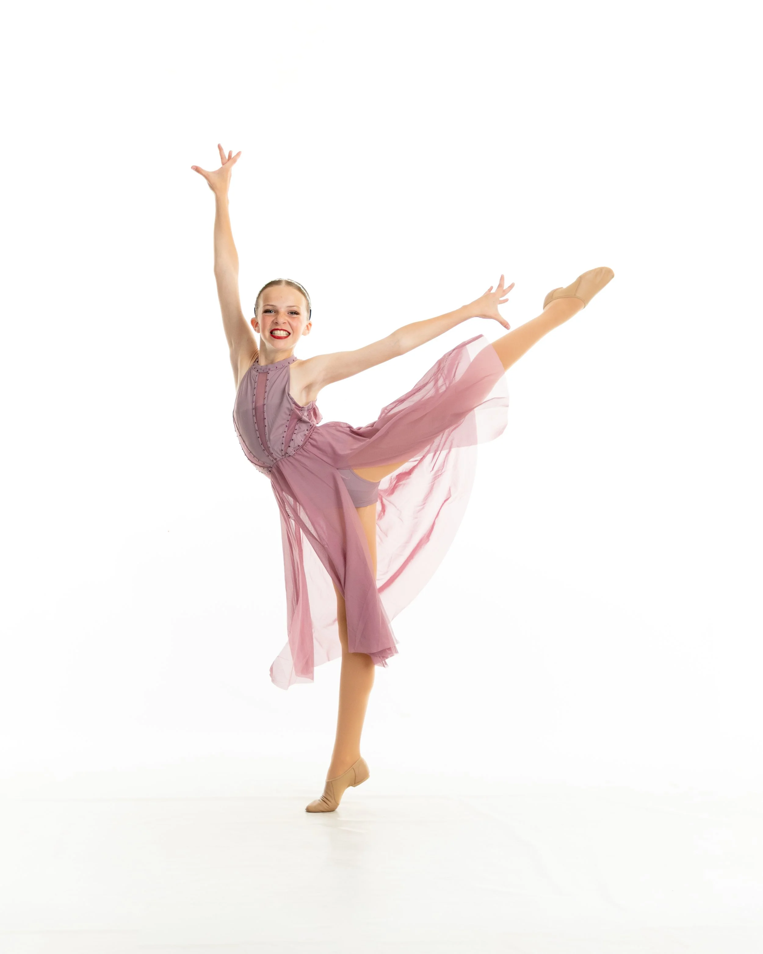 A young woman in a pink dance costume performing a ballet pose on a white background.