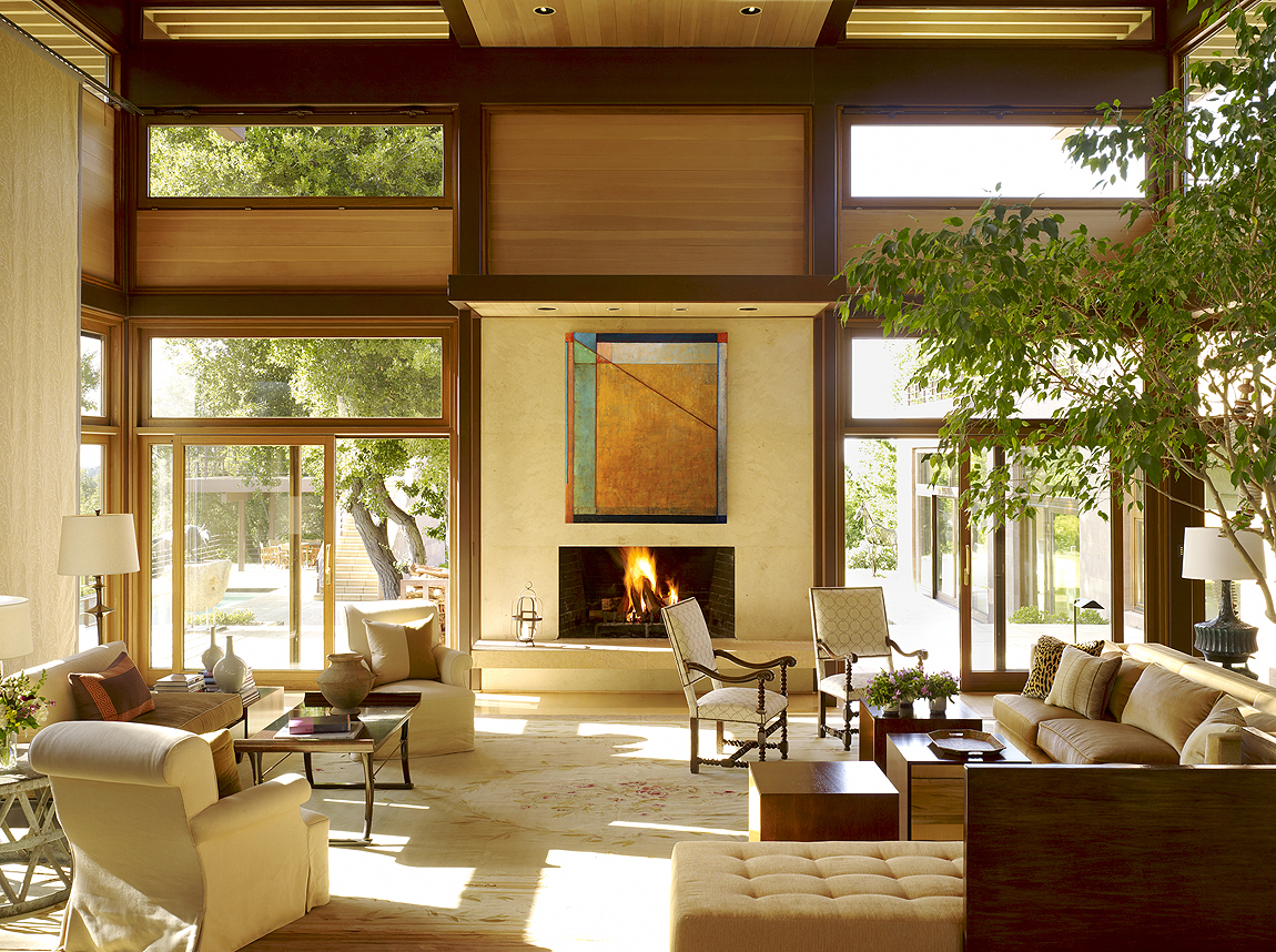 The owners of this Stanley Saitowitz-designed house in Los Gatos, California, wanted to enhance a sense of intimacy within their expansive living room. To soften the height and scale of the space, Matthews Studio added an interior tree and tall sliding panels of textured fabric, which serve as visual transitions from the crisp lines of the architecture to the upholstered furniture of the living area below. The panels also mitigate the strong afternoon sun. We complemented the owners’ existing antiques with new custom-designed contemporary furnishings to help integrate them with the architecture and bridge the eras. A few small splashes of intense hues and metallic elements add a lively note to the calm, neutral color palette. Architect: Stanley Saitowitz, Natoma Architects Photography: Matthew Millman