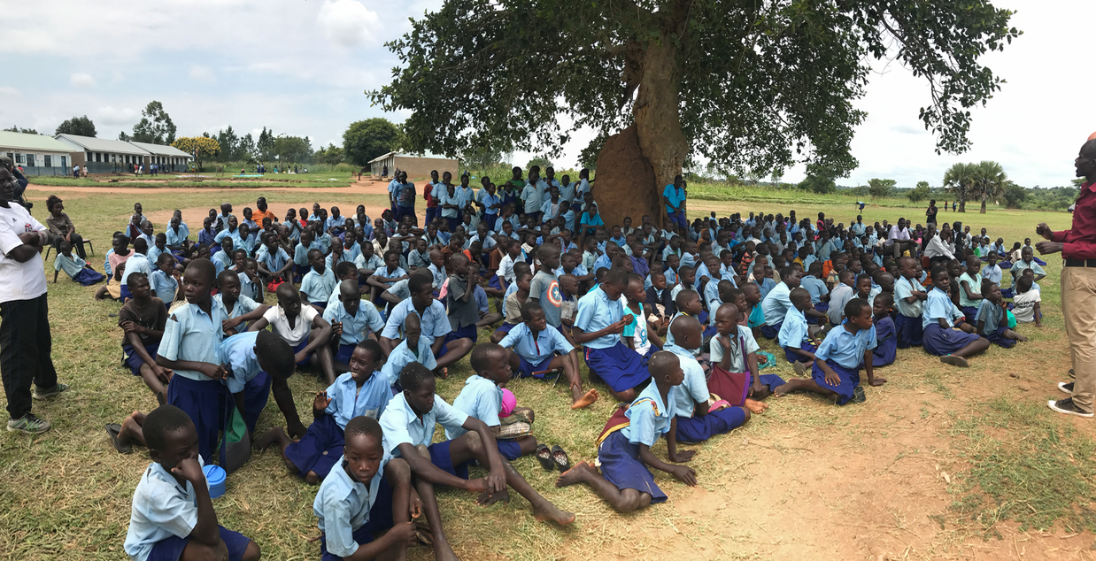 All of the students at Odek Primary School coming together after playing games and listening to our message in groups.