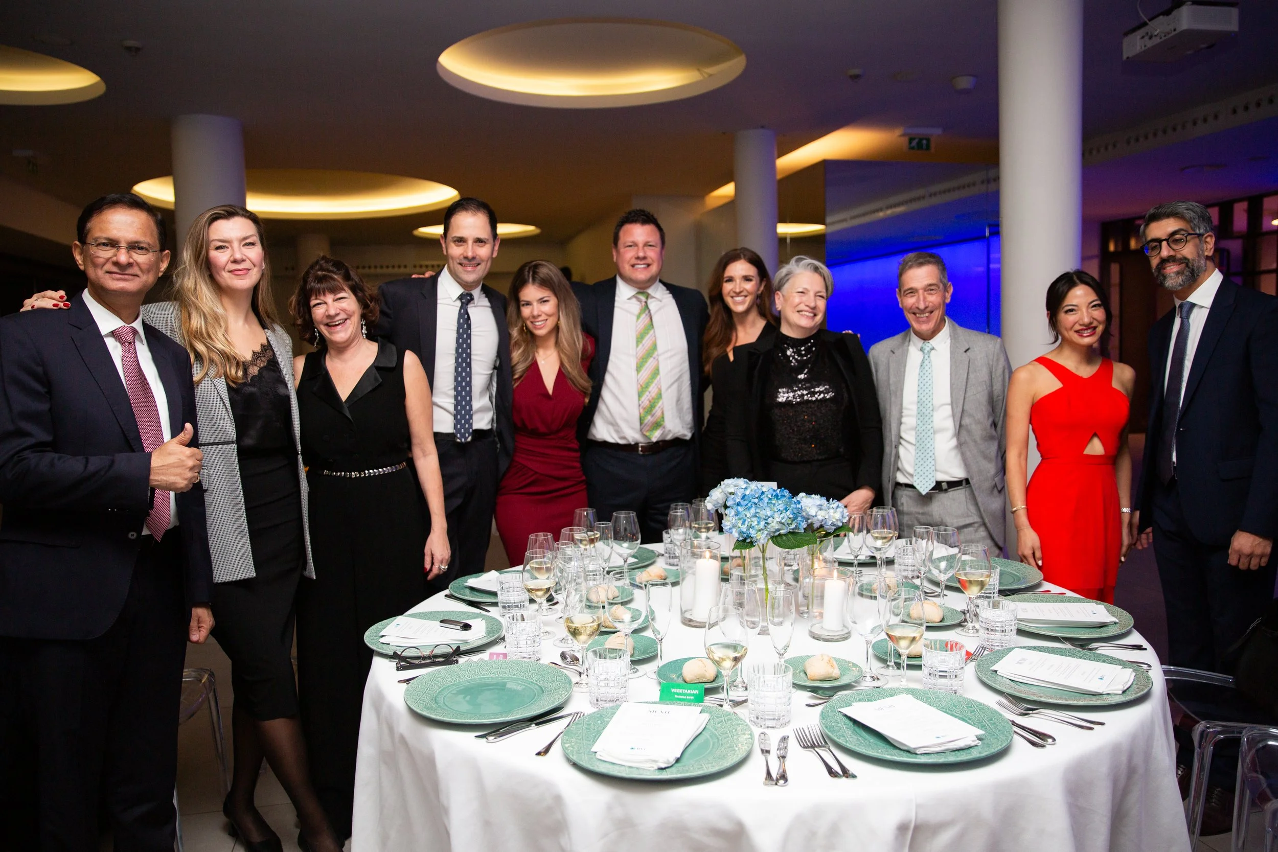 Professional corporate event photography in Lisbon, Portugal, capturing a group of guests smiling together for a posed photograph at their dinner table. This image highlights the connections, camaraderie, and memorable moments shared during a corpora