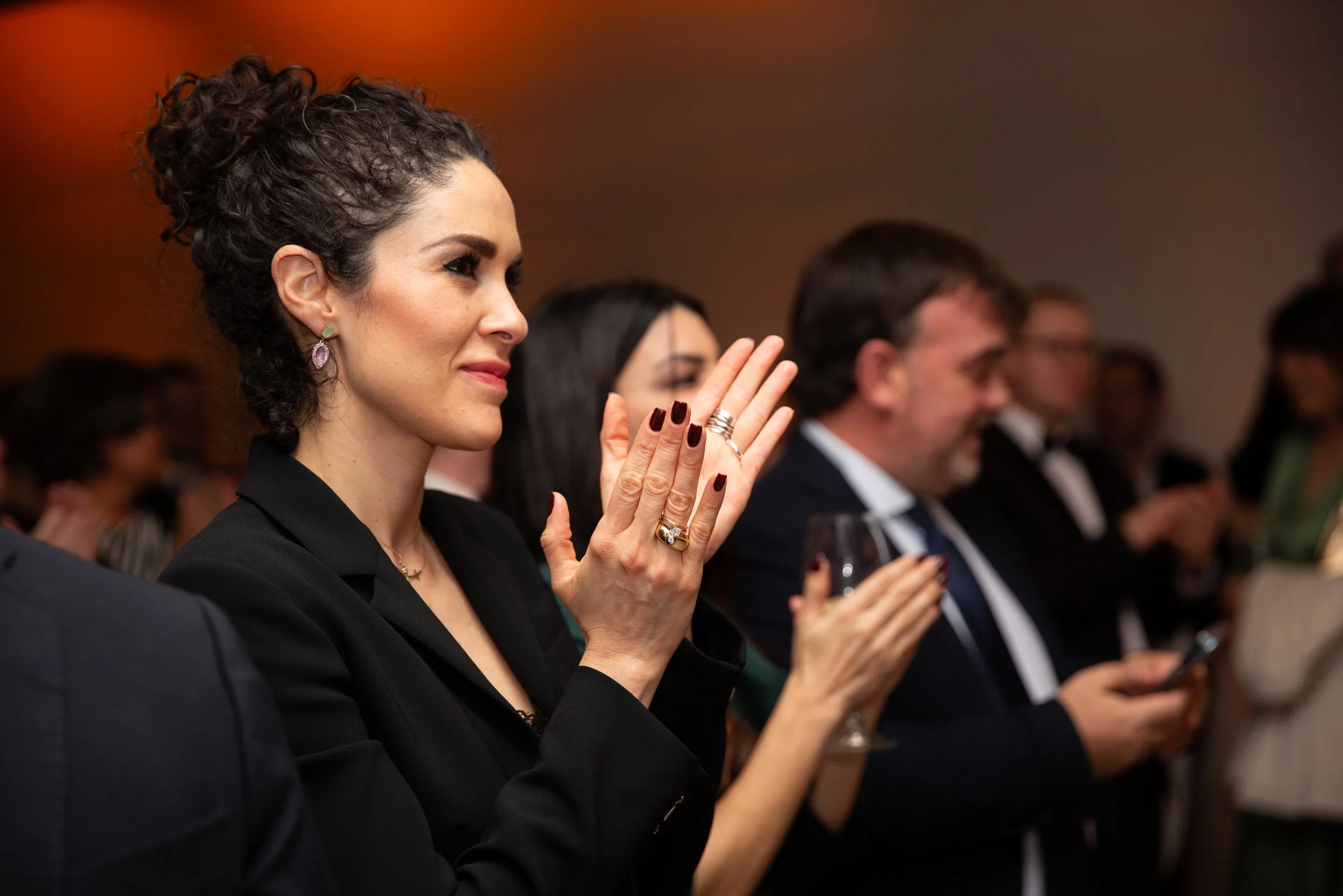 A candid image of a woman clapping in the audience listening to a presentation during a corporate event in Lisbon.