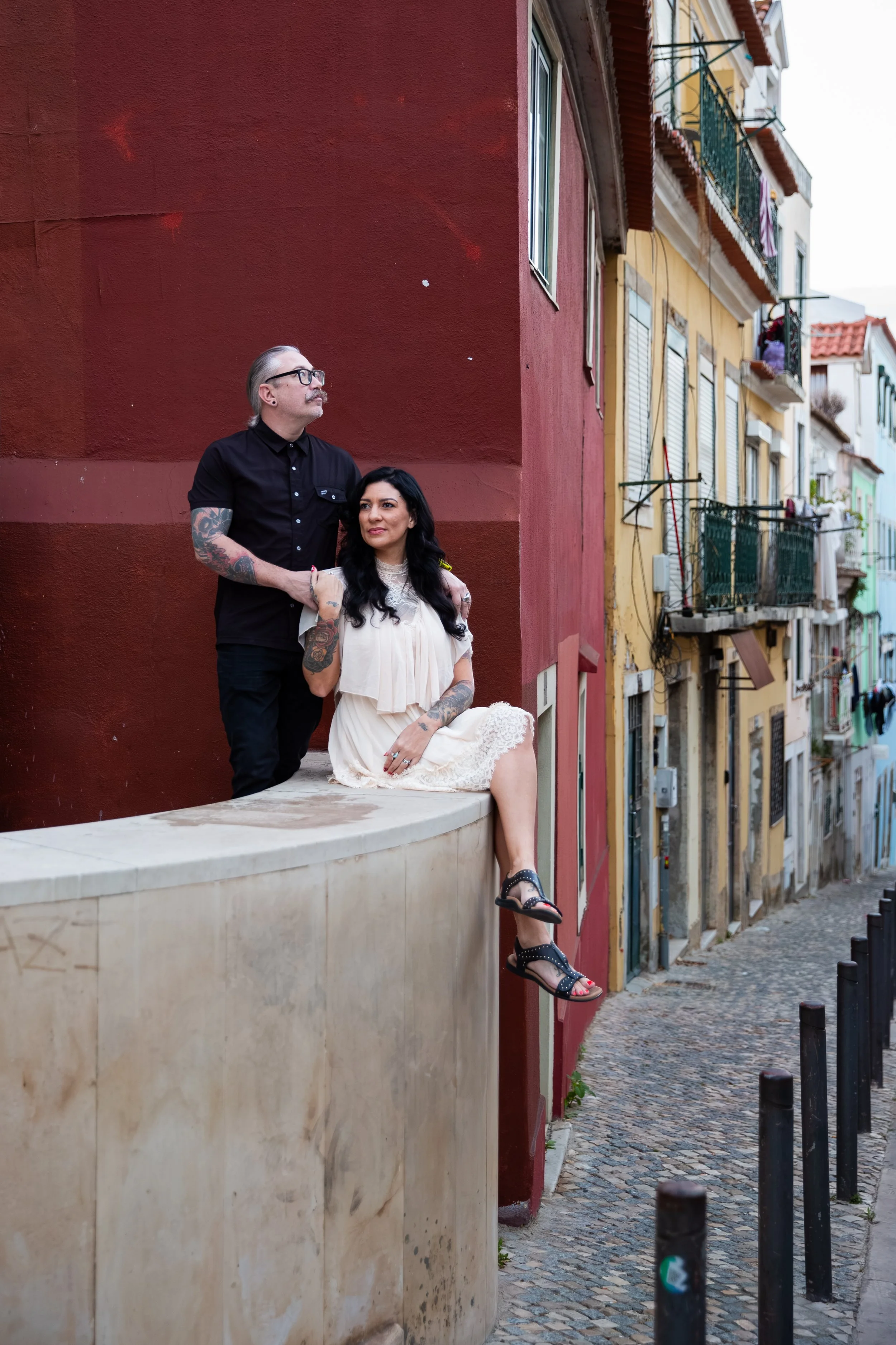 Couples vacation portrait session in Lisbon with a couple seated on the steps of a colorful building.