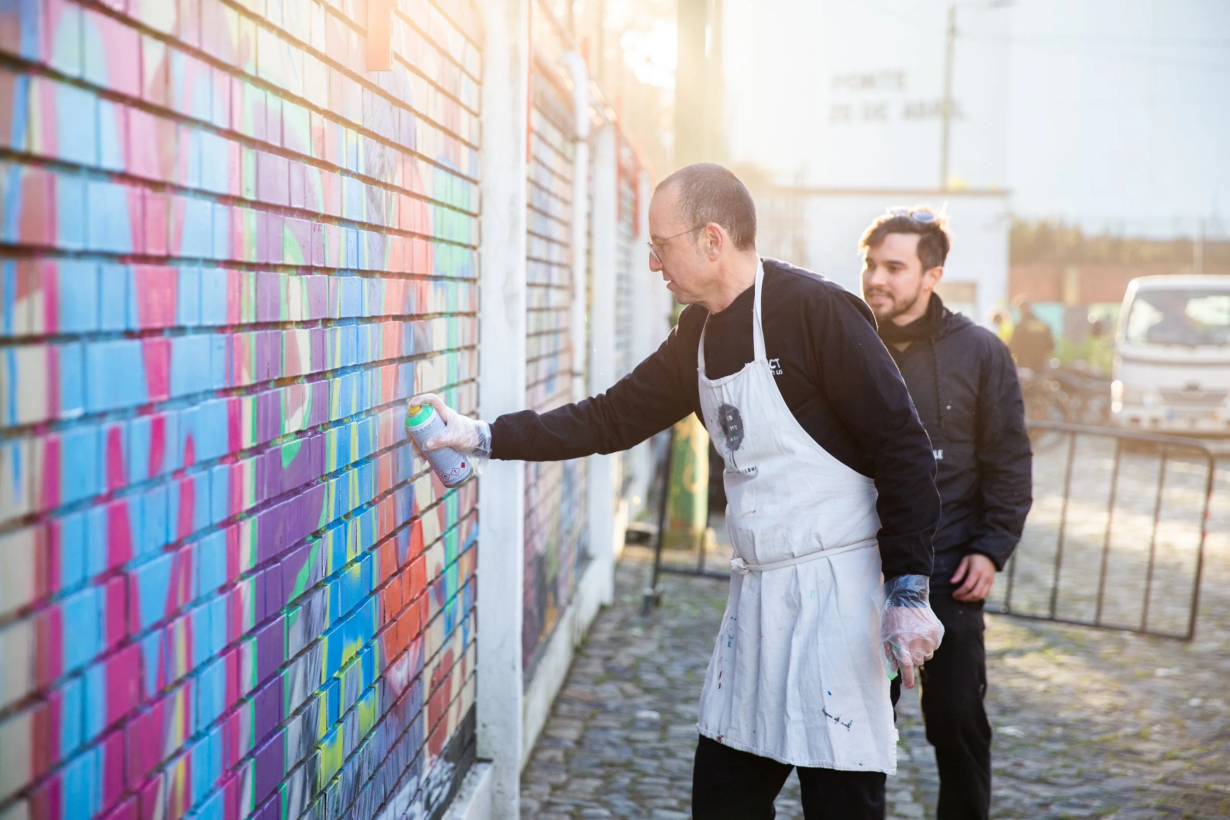 A group of corporate employees learning graffiti techniques during a creative team-building workshop in Lisbon, Portugal. Professional event photography captures the fun, collaboration, and hands-on experiences that bring teams together outside the t