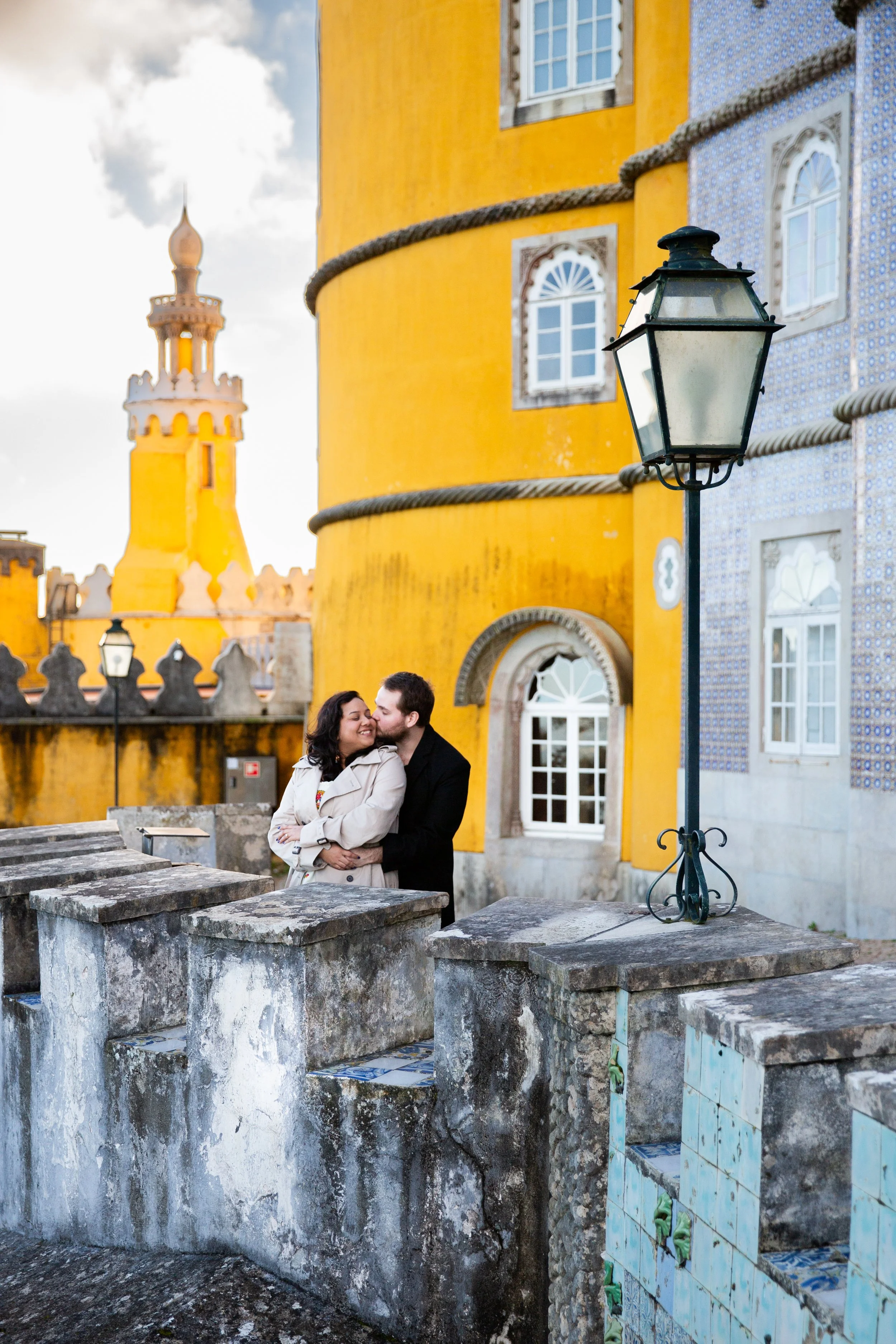 A couple standing close together and smiling, at a balcony at Pena Palace in Sintra.
