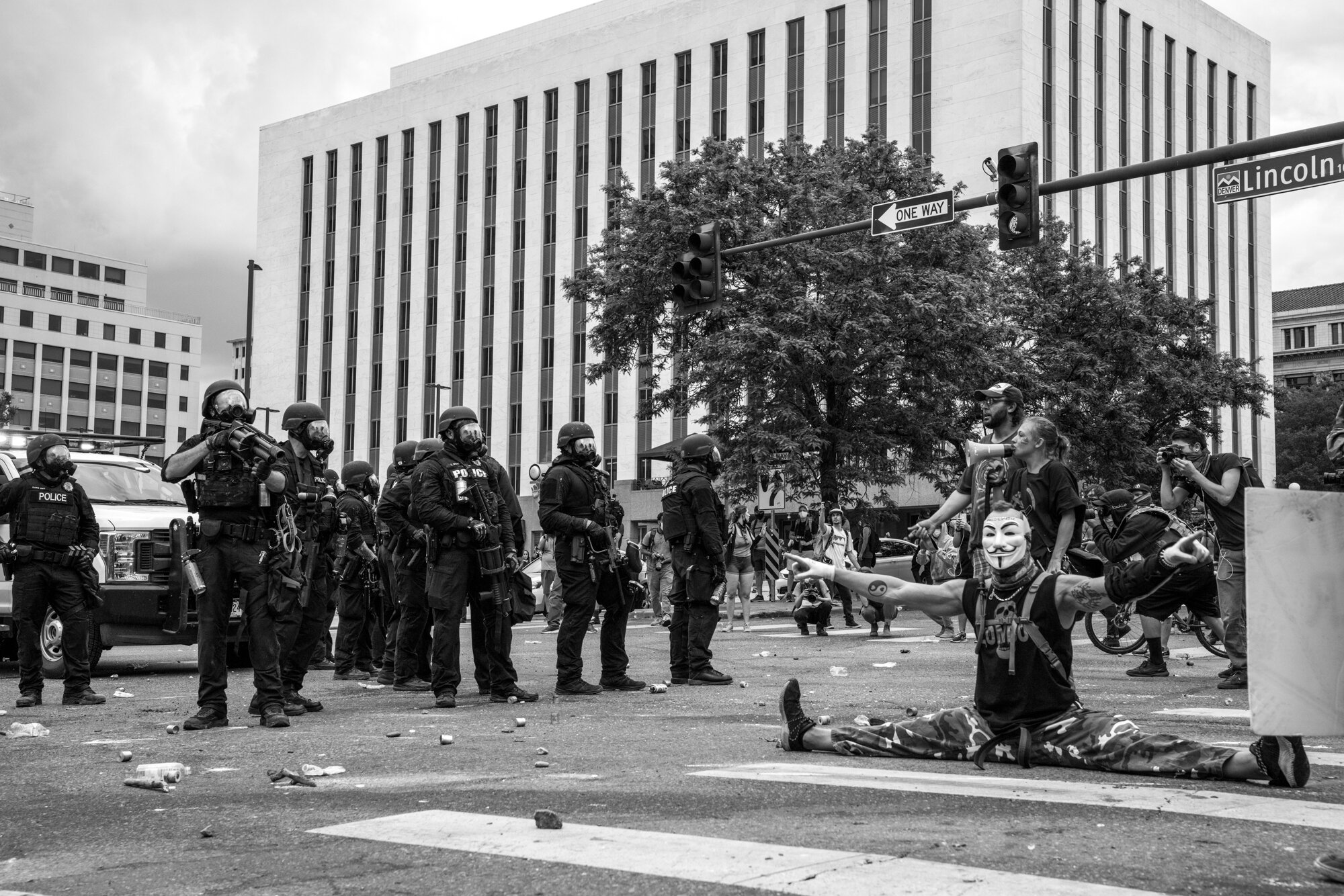 One protester does the splits, while others shout at and take photos of police in riot gear. 5/30/2020.