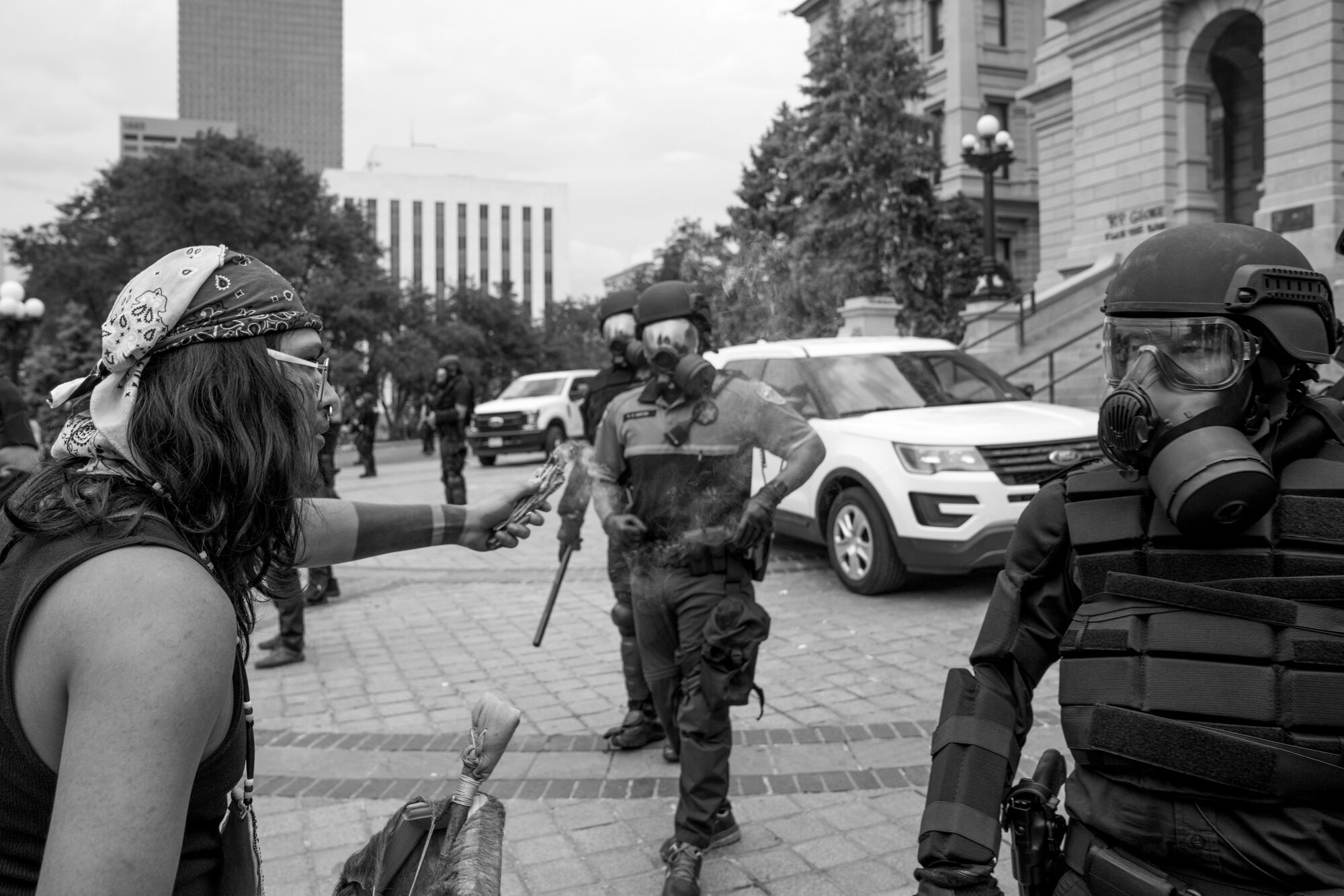 A protester holds a bundle of burning sage in front of a police officer. 5/30/2020.