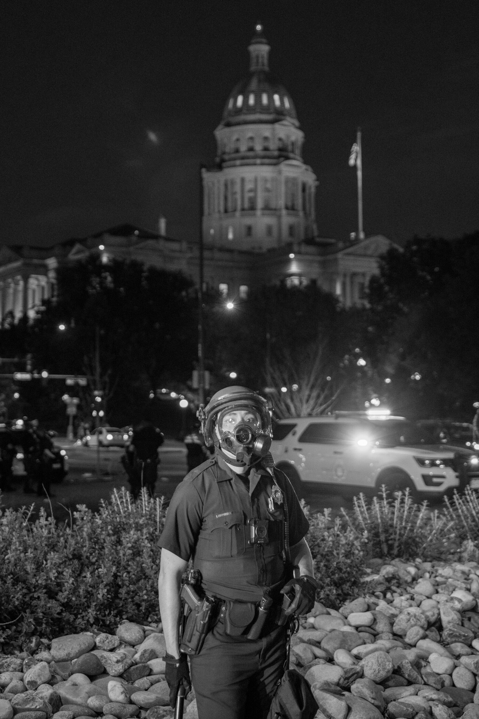A police officer holds his baton with the Colorado state capitol building in the background. 5/29/2020.
