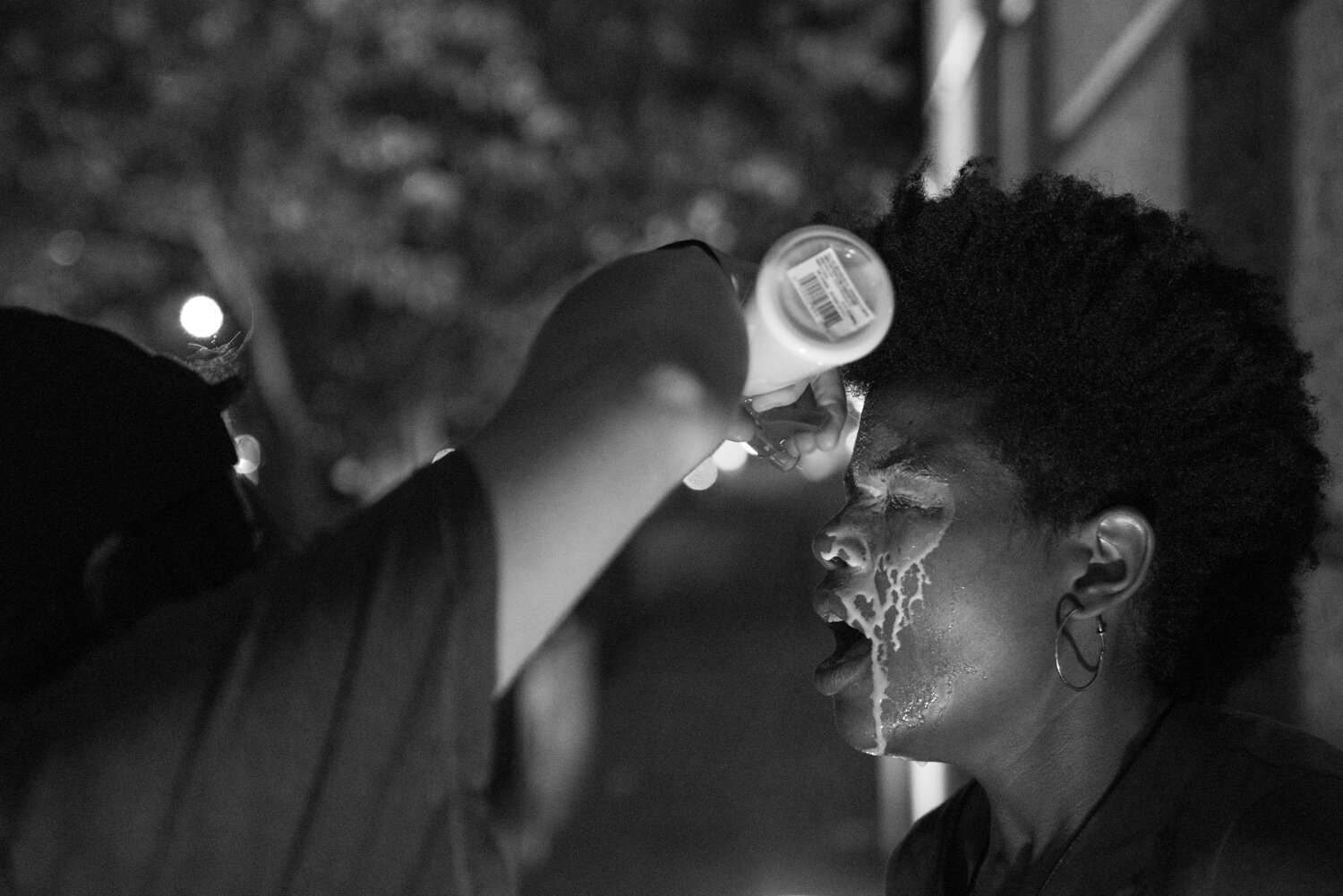 A protester who was just tear gassed gets a milk solution sprayed into her eyes to subdue the effects. 5/29/2020.