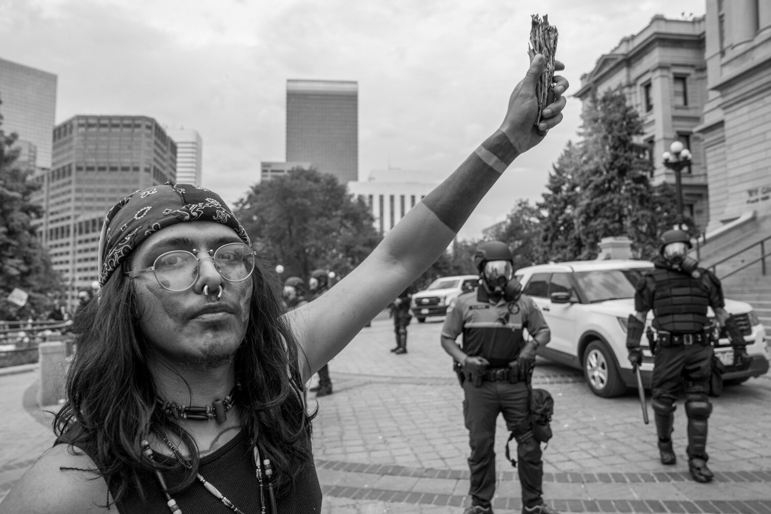 A protester raises his burning sage in the air while police stand in the background. 5/30/2020.