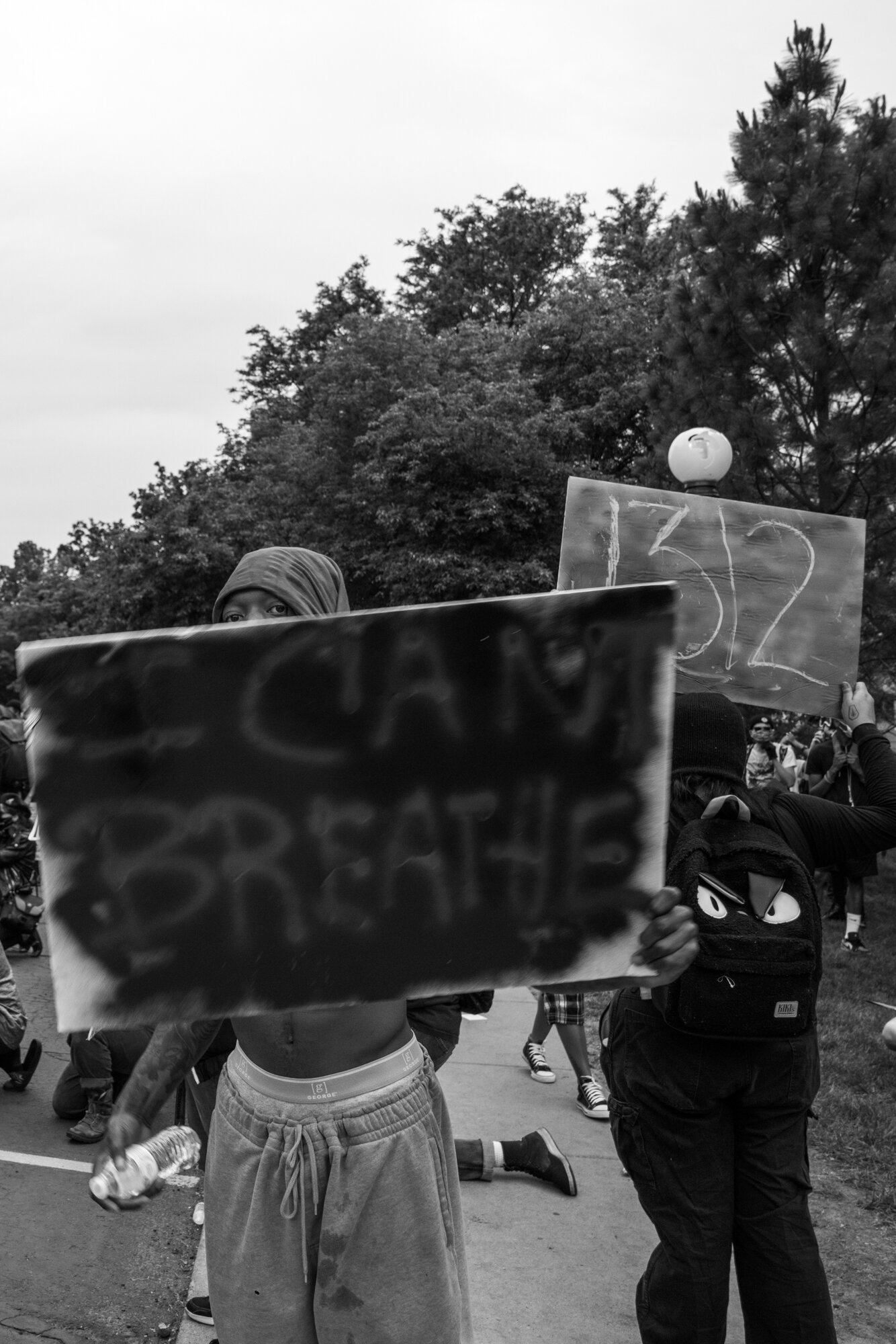 A man peeks from behind his sign outside of the state capitol building. 5/30/2020.