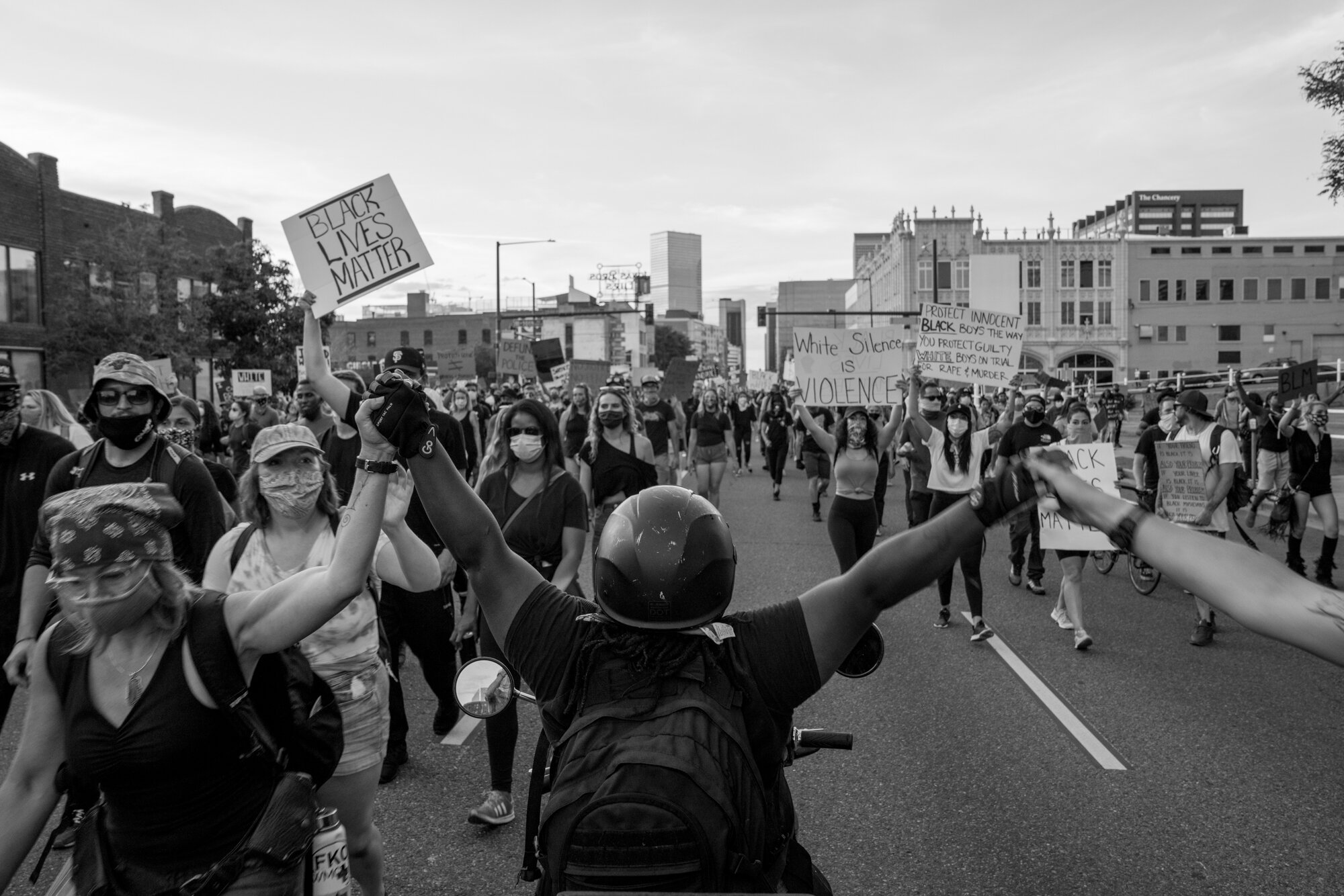 A protester on her moped holds out her hands to those marching. 6/02/2020.