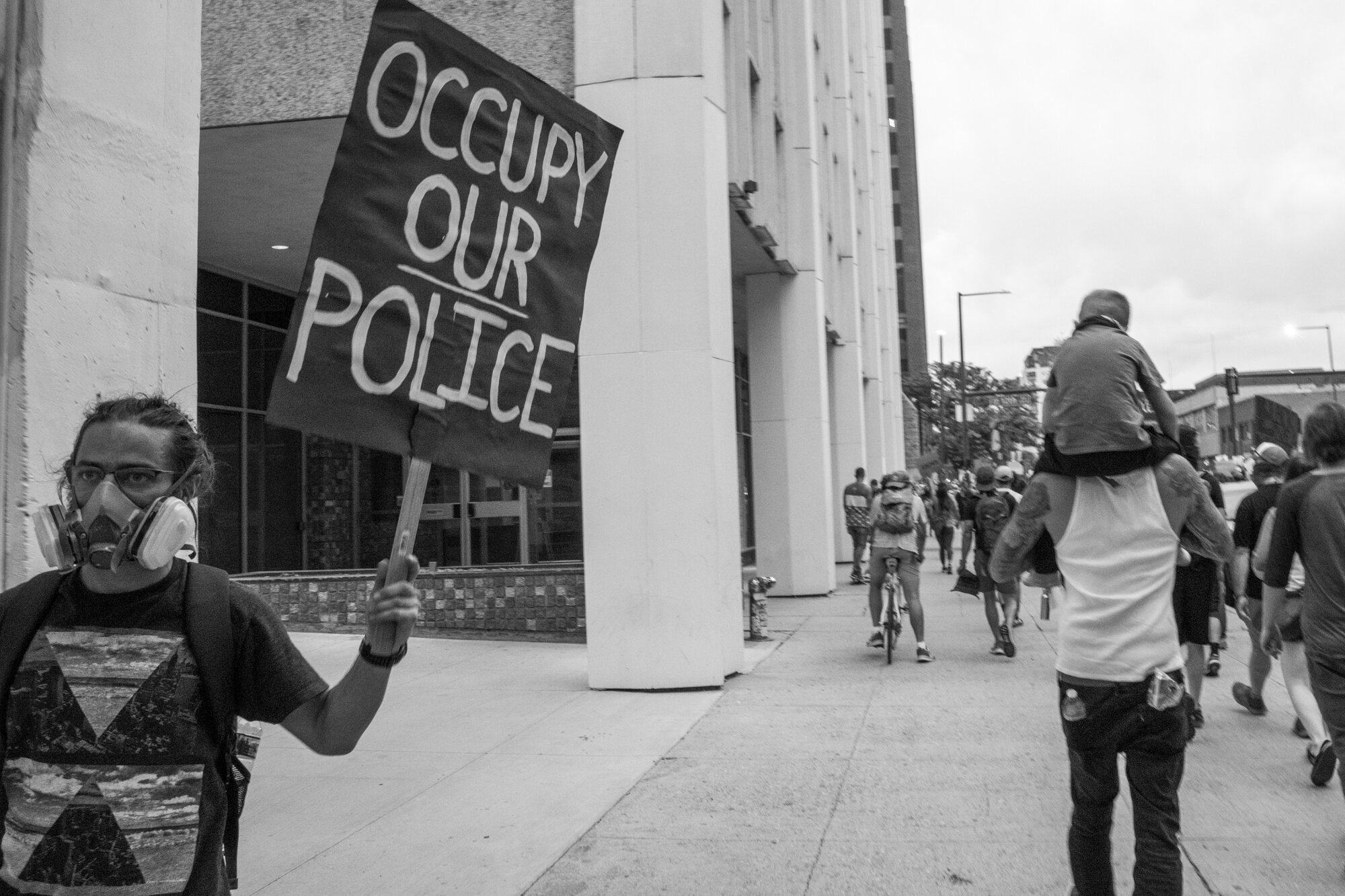A protester in a gas mask walks in the opposite direction of the protesters marching. 6/02/2020.